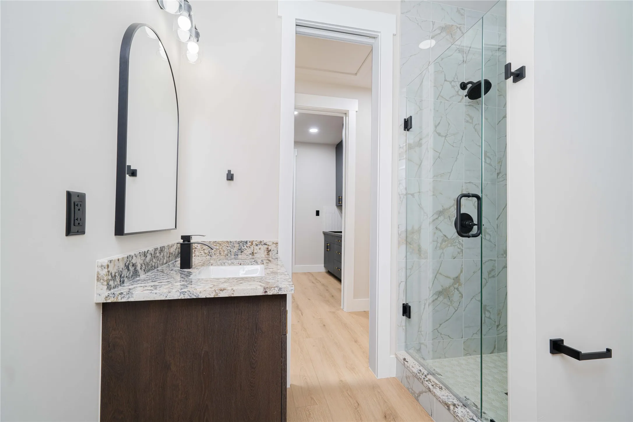Bathroom featuring a dark wood-finish vanity with a light-toned granite countertop, an undermount sink, and a matte black faucet