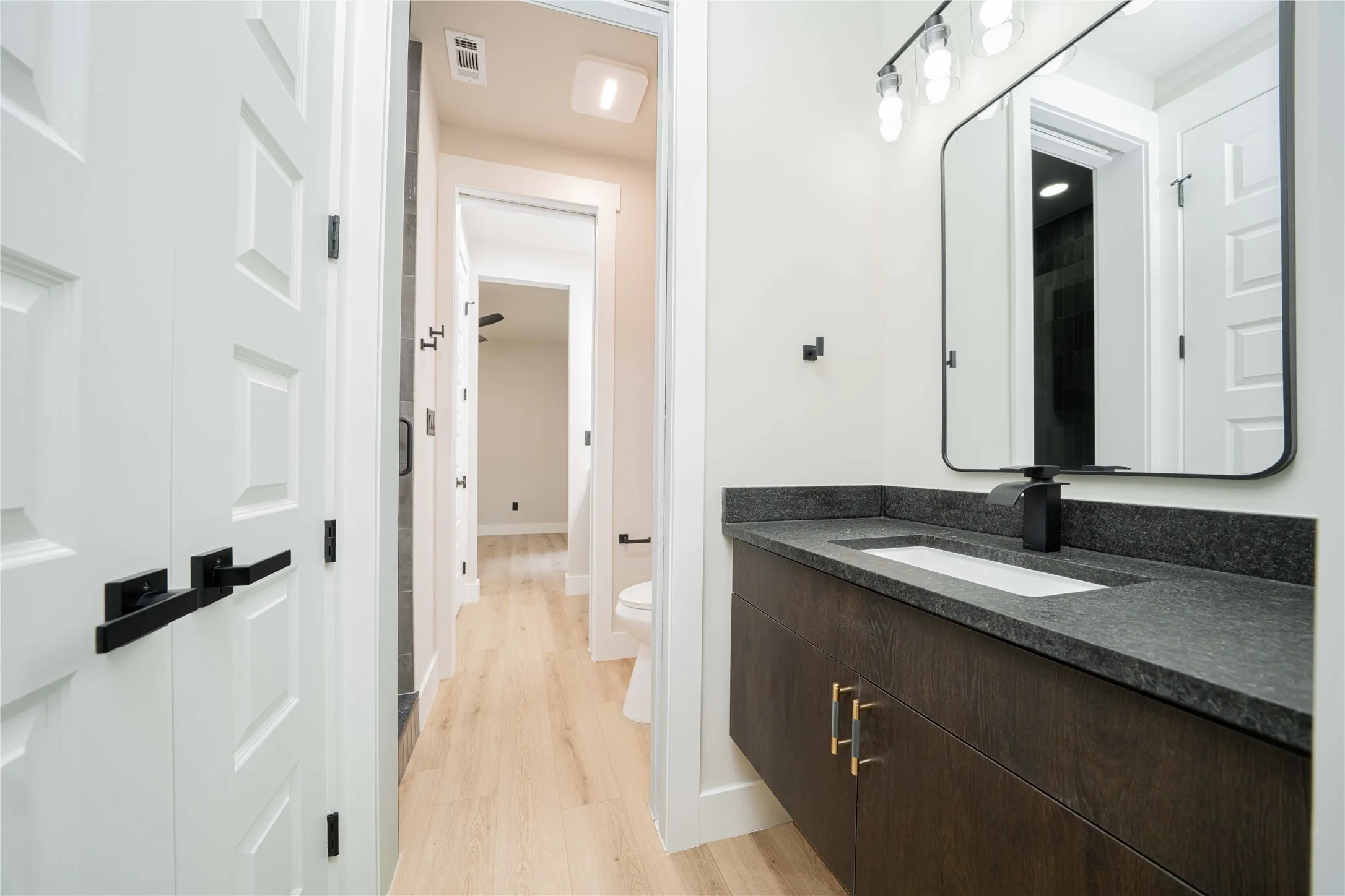 Floating vanity with dark wood-finish cabinetry, a dark speckled countertop, and an integrated rectangular sink
