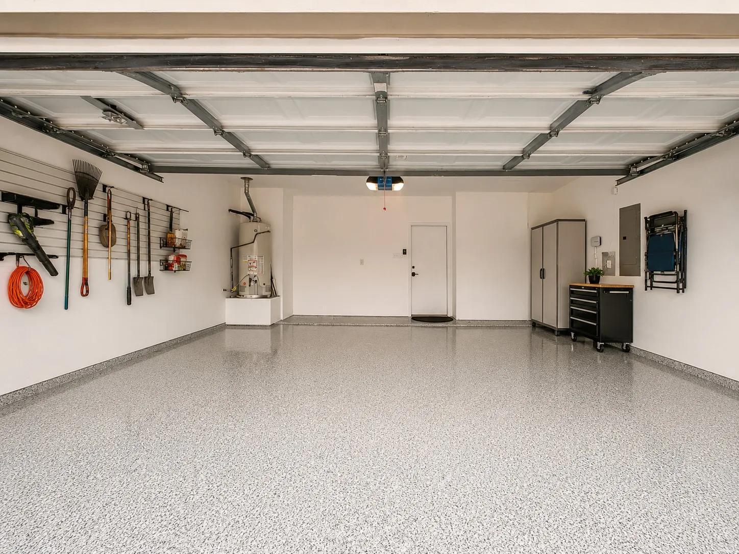 Spacious garage featuring a durable epoxy speckled floor finish, white painted walls, and built-in storage solutions