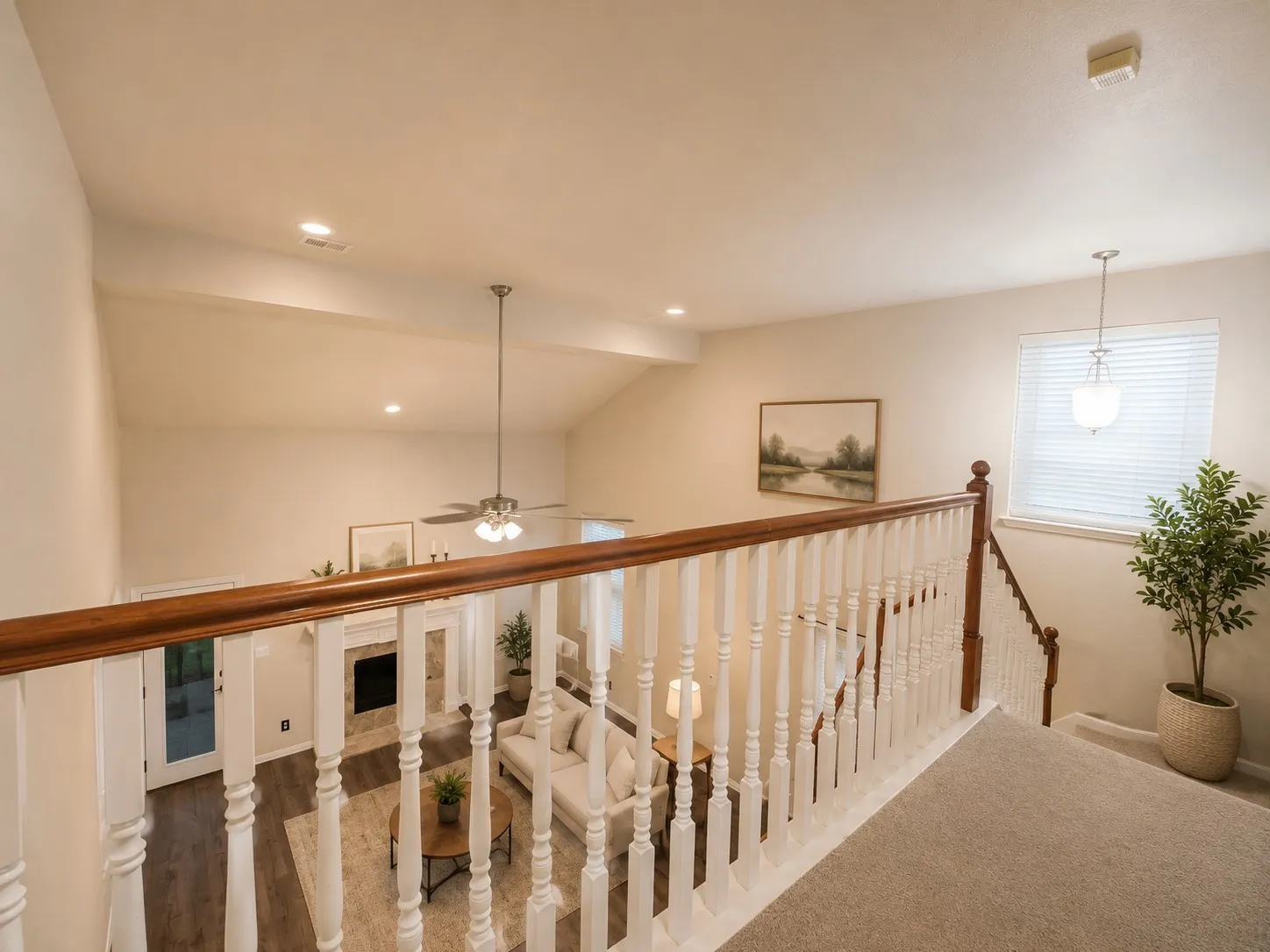 Overlooking loft area featuring a natural wood handrail with white balusters