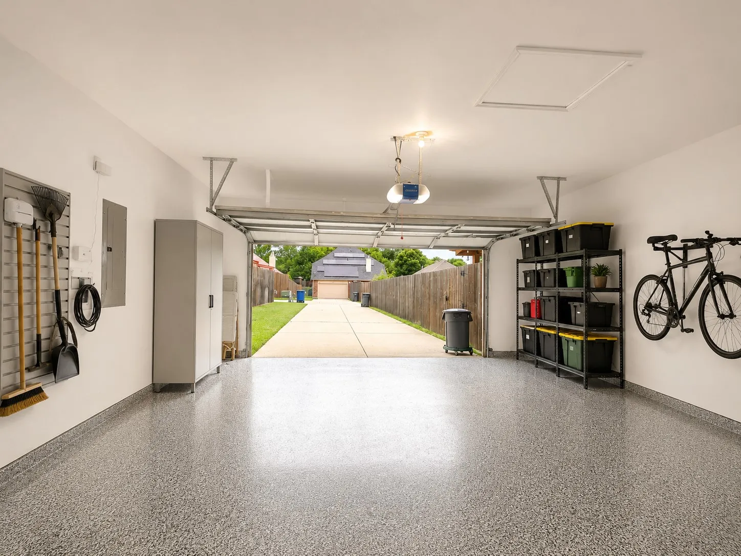 Spacious garage featuring a speckled epoxy floor, automatic garage door opener, and attic access panel