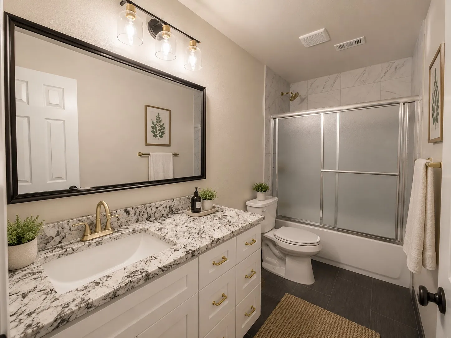 White vanity with gold-tone hardware, a drop-in sink, and a granite countertop