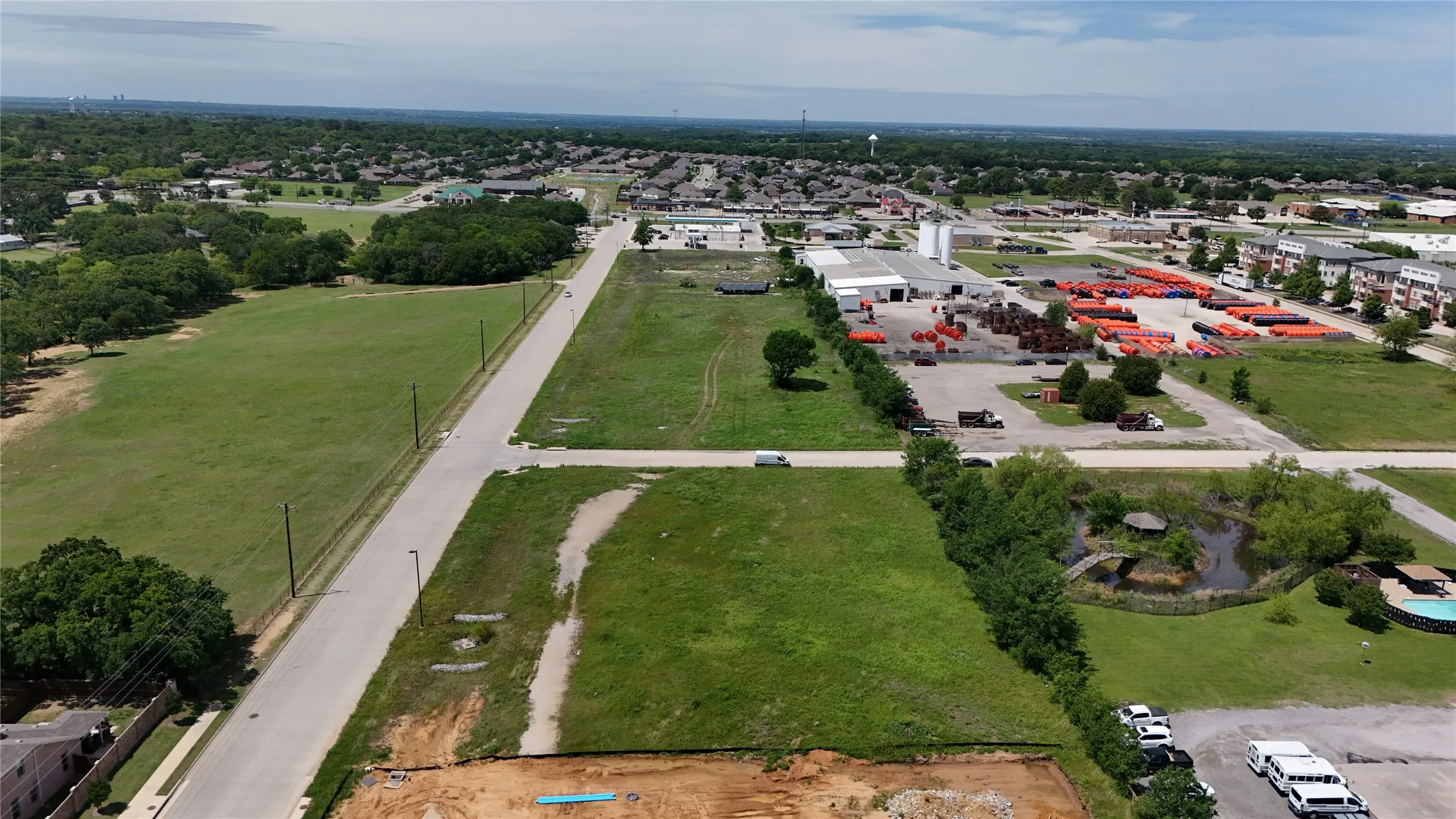 Expansive green fields bordering a paved road, with additional undeveloped land