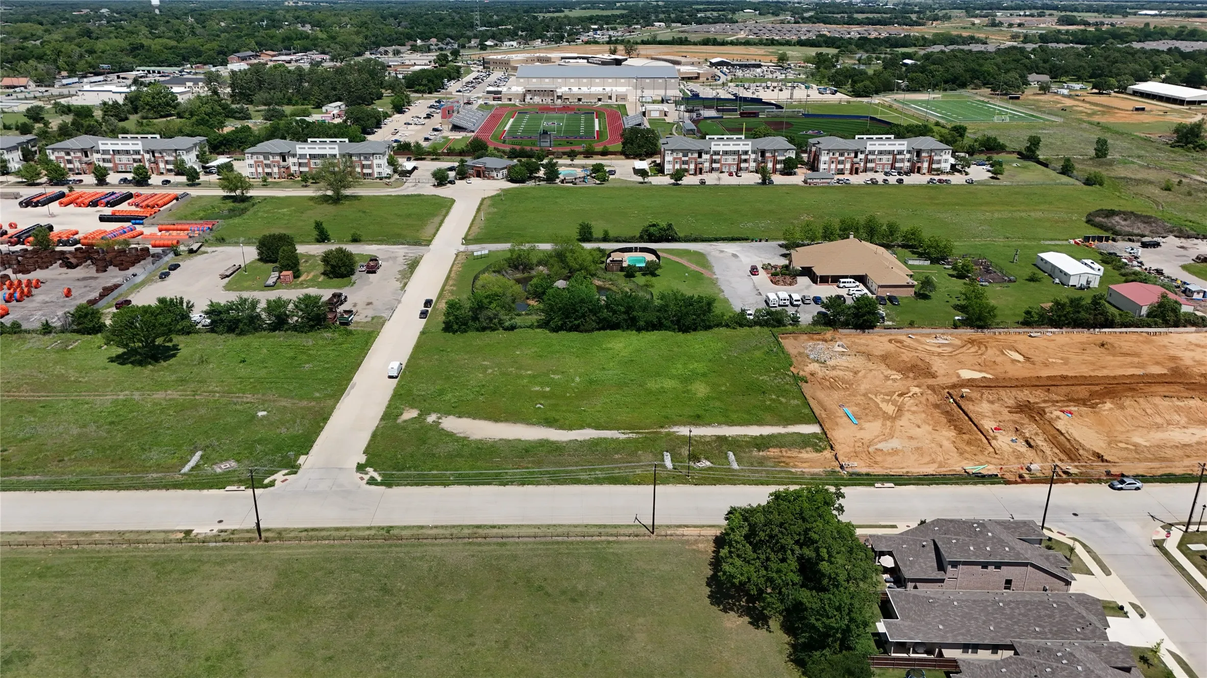 Expansive undeveloped land parcel with surrounding residential and commercial structures