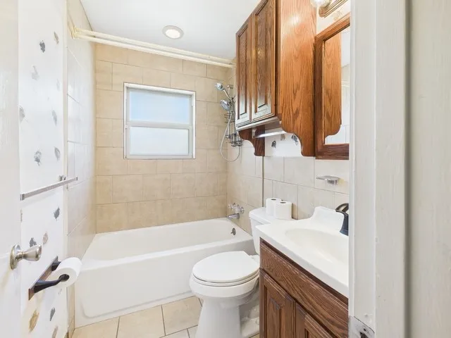 Bathroom featuring toilet, tile walls, vanity, shower / bathtub combination, and tile patterned flooring