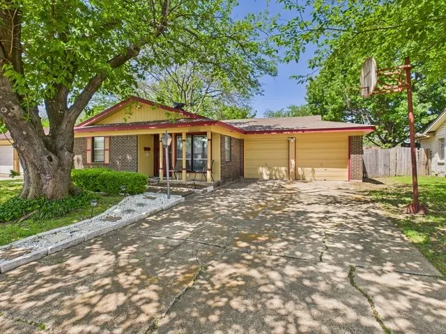 Single story home featuring an attached garage, covered porch, fence, brick siding, and driveway