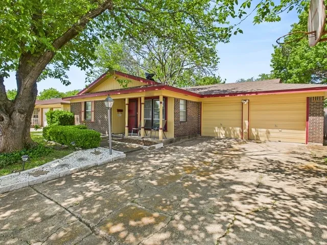 Ranch-style house with driveway, a garage, covered porch, and brick siding