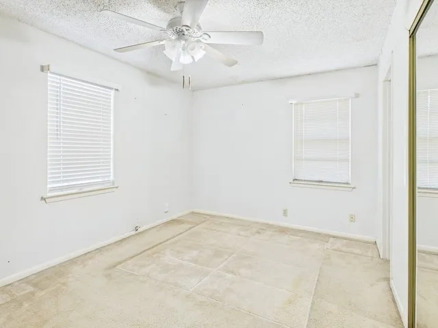 Spare room with ceiling fan, carpet flooring, baseboards, and a textured ceiling