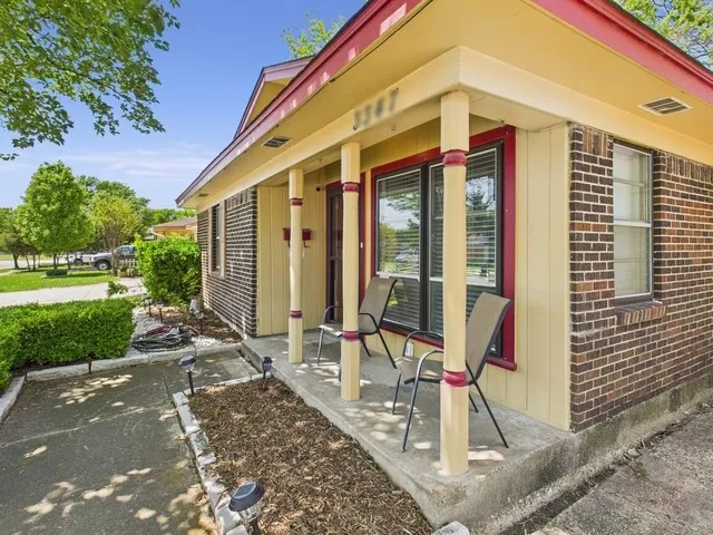 Doorway to property with a porch, brick siding, and visible vents