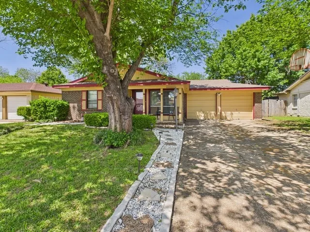 Ranch-style home featuring a garage, fence, a front lawn, brick siding, and driveway
