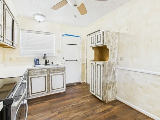 Kitchen with dark wood-type flooring, a textured ceiling, a sink, and a ceiling fan