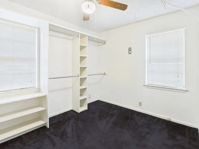 Walk in closet featuring dark colored carpet and ceiling fan