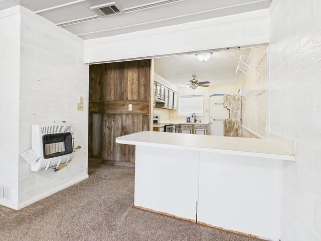 Kitchen with stainless steel range with electric cooktop, a peninsula, a ceiling fan, visible vents, and heating unit