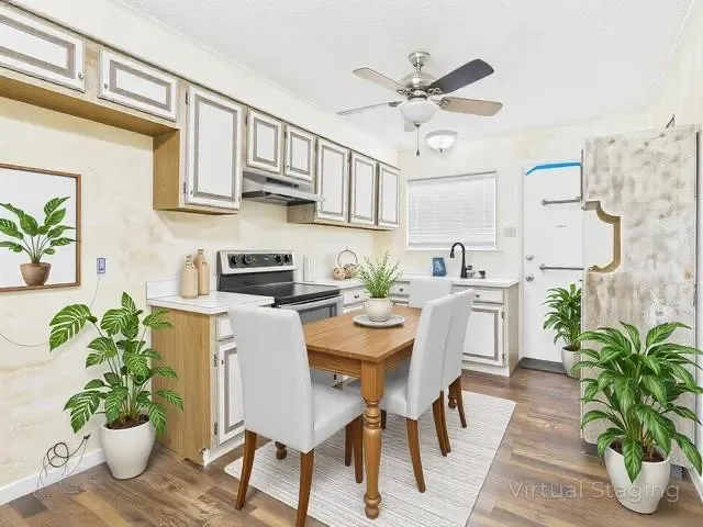 Virtual Staging in Kitchen with ceiling fan, stainless steel electric stove, under cabinet range hood, wood finished floors, and light countertops