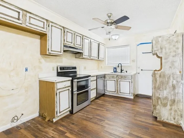 Kitchen featuring light countertops, under cabinet range hood, ceiling fan, stainless steel appliances, and a sink