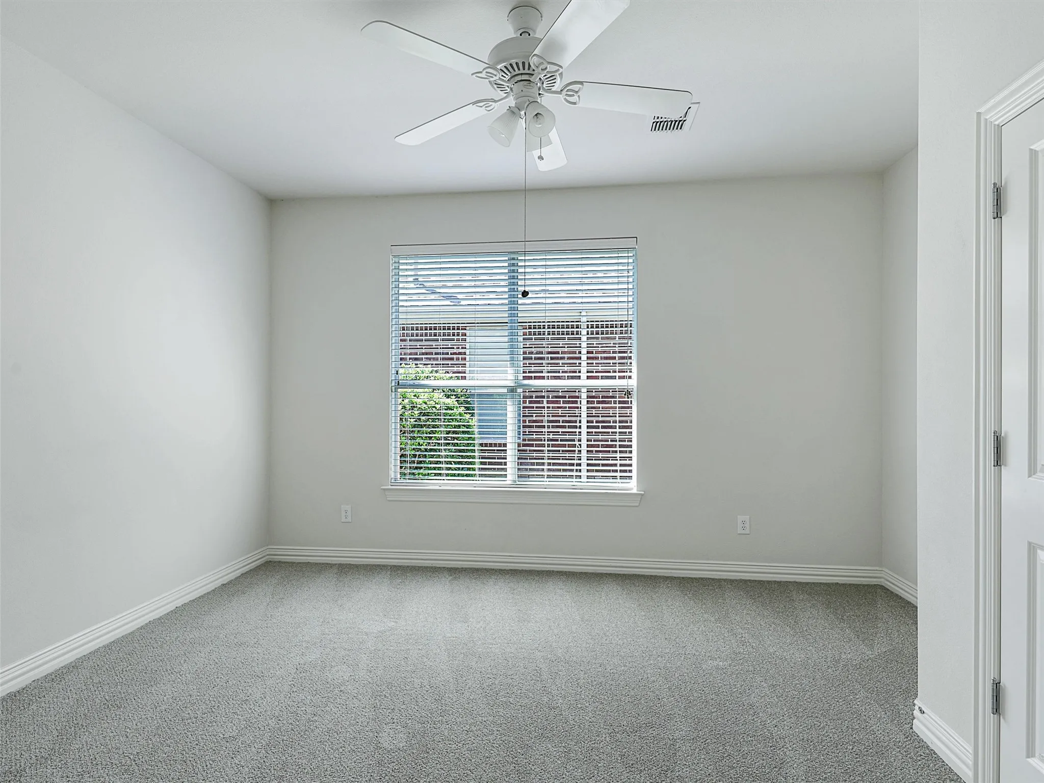 Carpeted empty room with baseboards and a ceiling fan