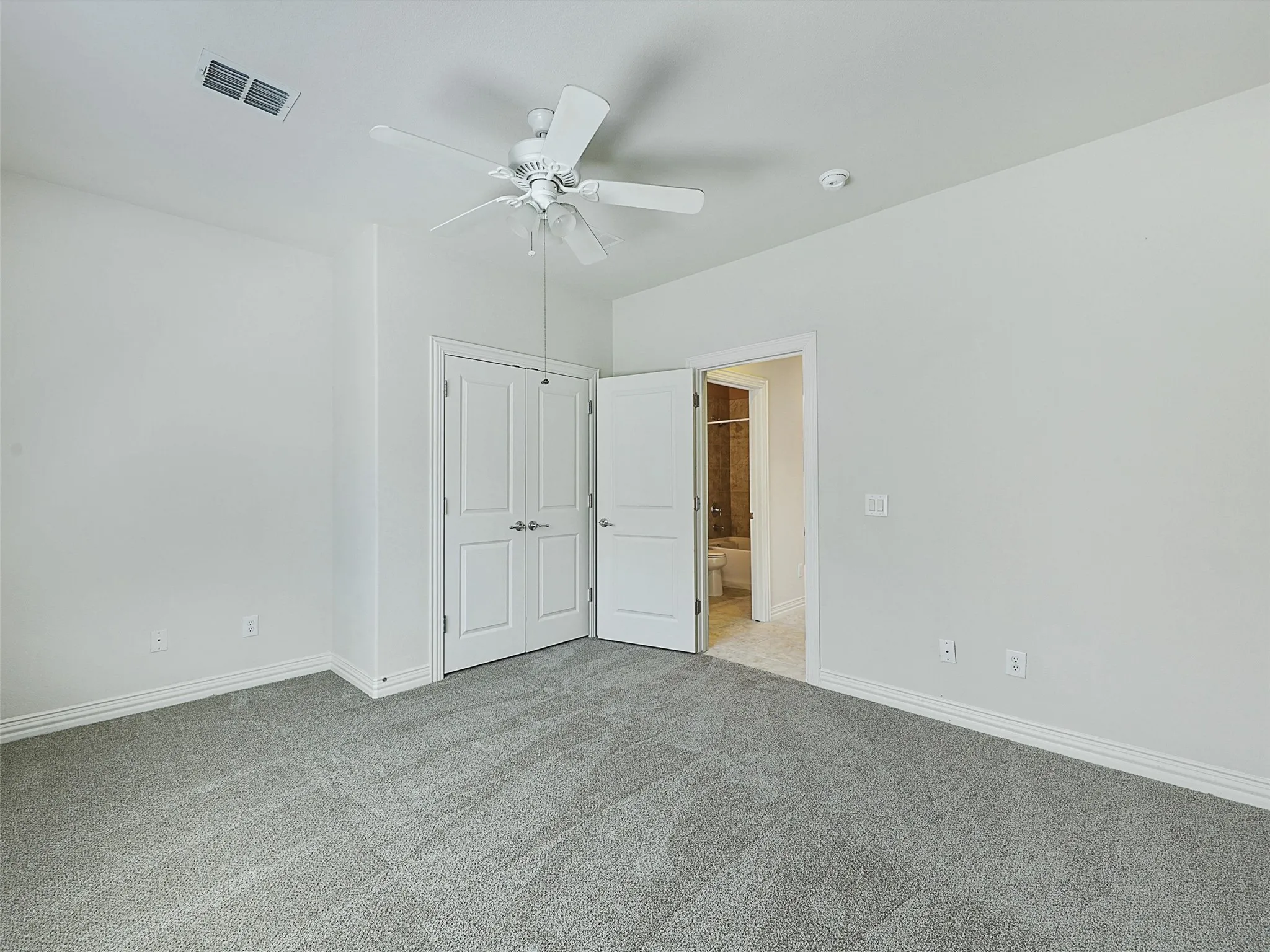 Unfurnished bedroom with carpet floors, a ceiling fan, ensuite bath, and a closet