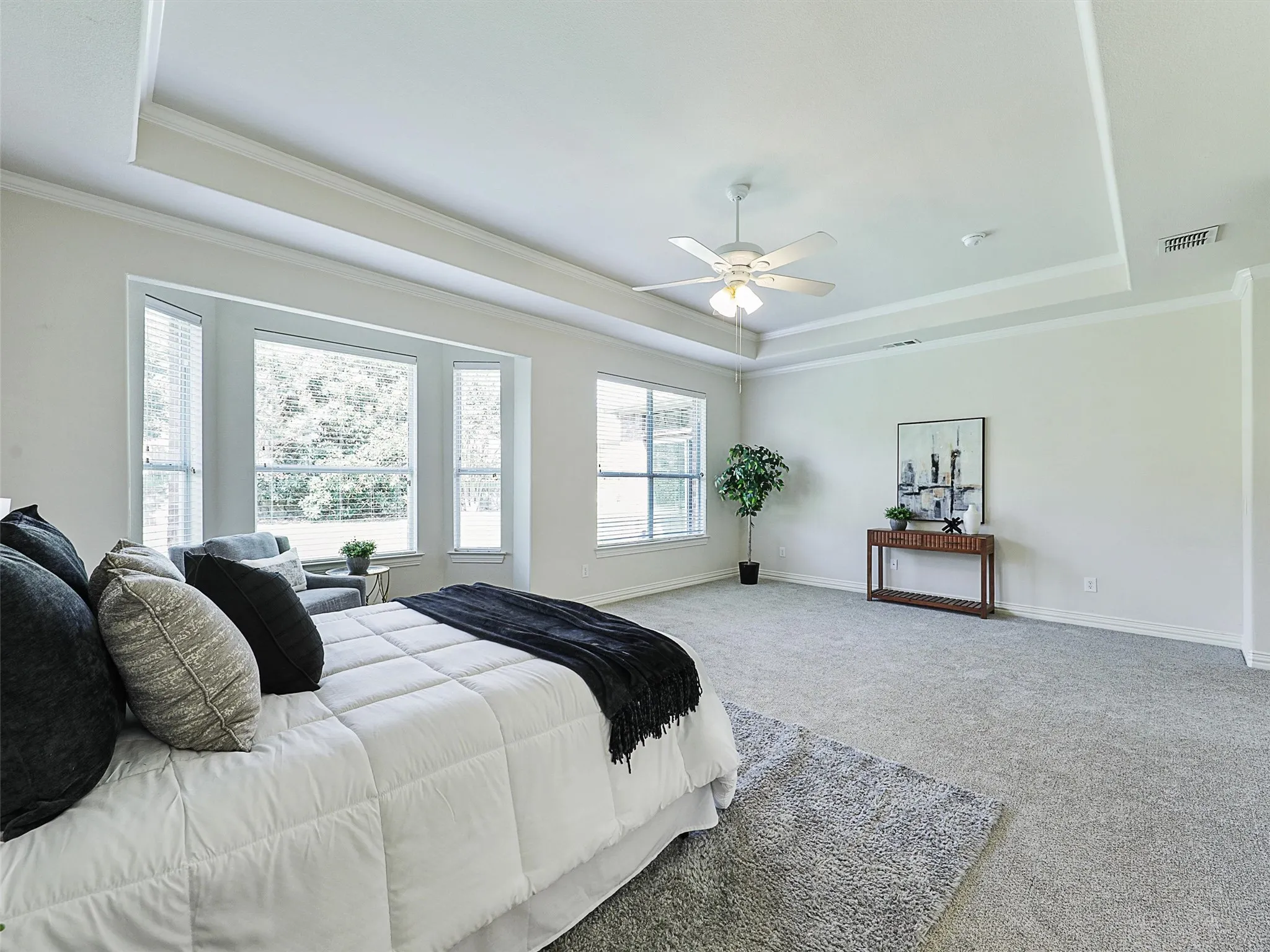 Primary Bedroom featuring a tray ceiling, crown molding, carpet, and ceiling​​‌​​​​‌​​‌‌​‌‌​​​‌‌​‌​‌​‌​​​‌​​ fan