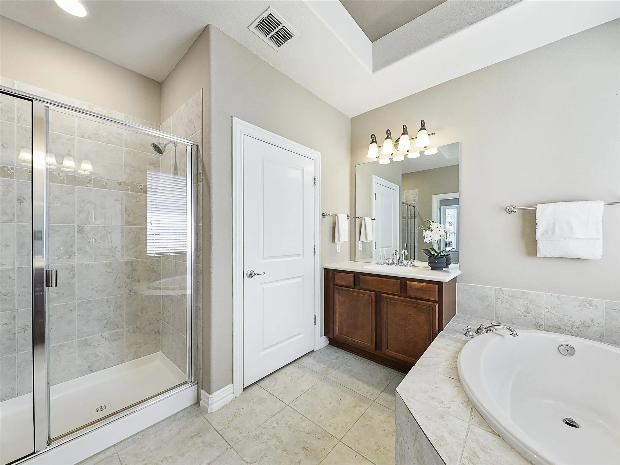 Bathroom with a bath, a stall shower, vanity, and light tile patterned flooring
