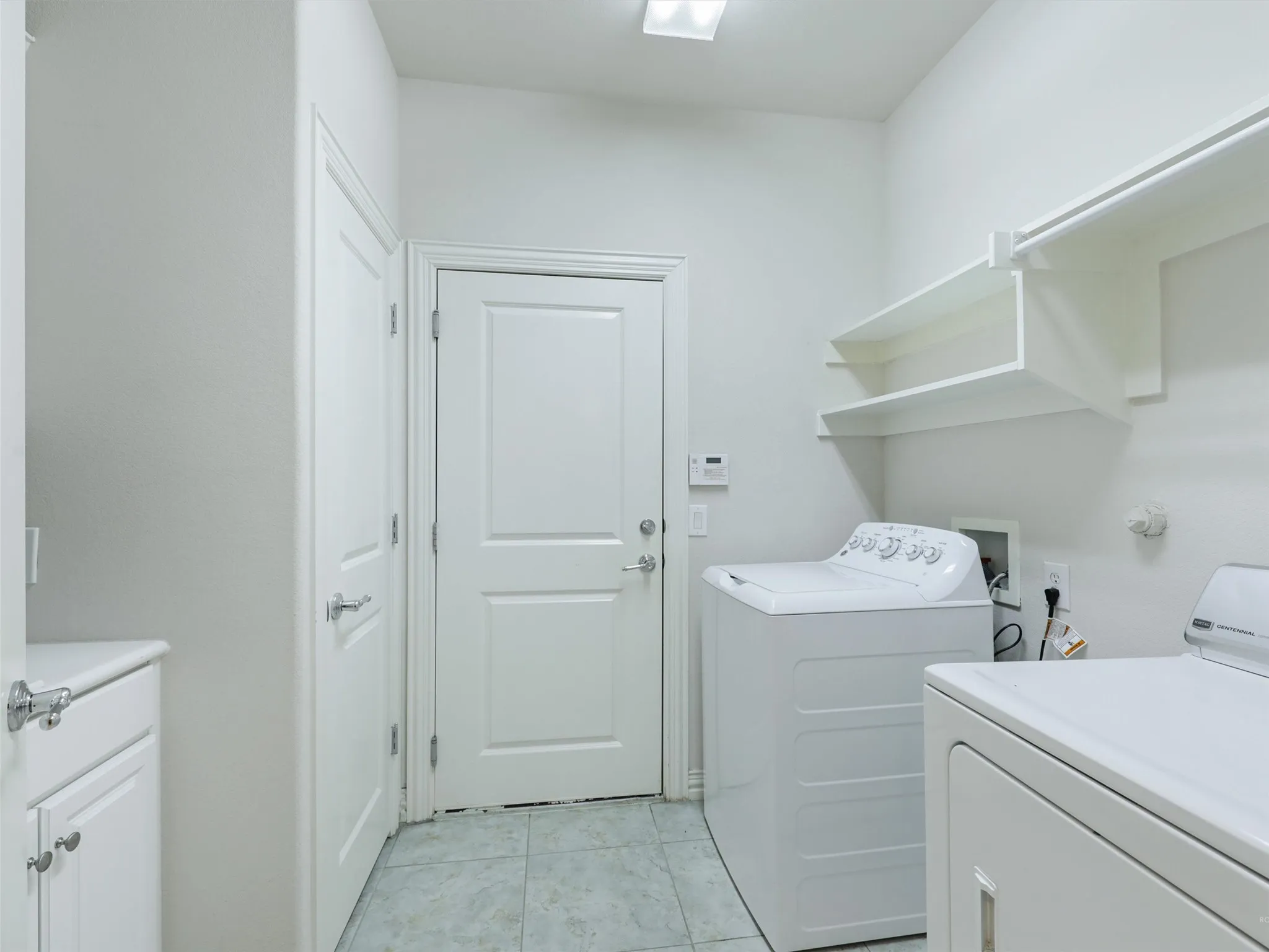 Washroom with light tile patterned floors and washer and clothes dryer
