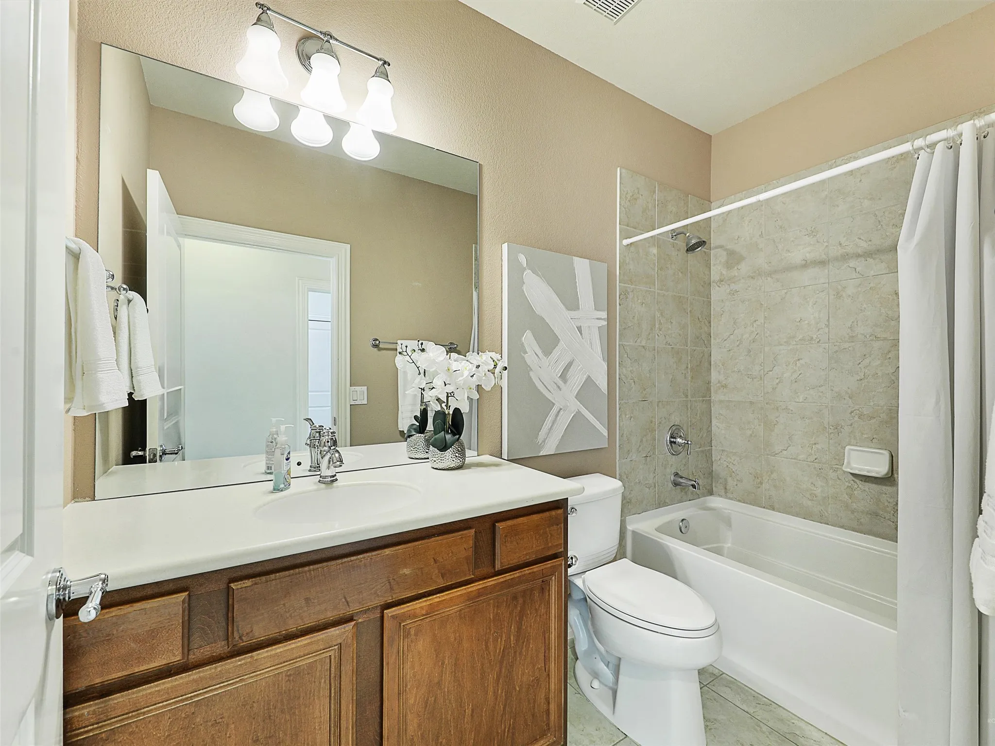 Full bath featuring shower / tub combo, vanity, and light tile patterned floors