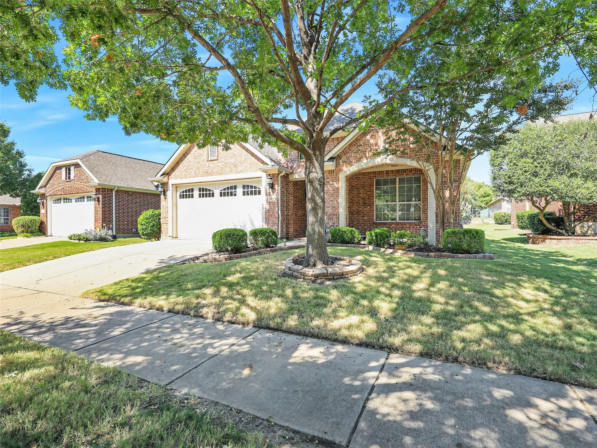 Traditional-style home with a front yard, driveway, brick siding, and an attached garage