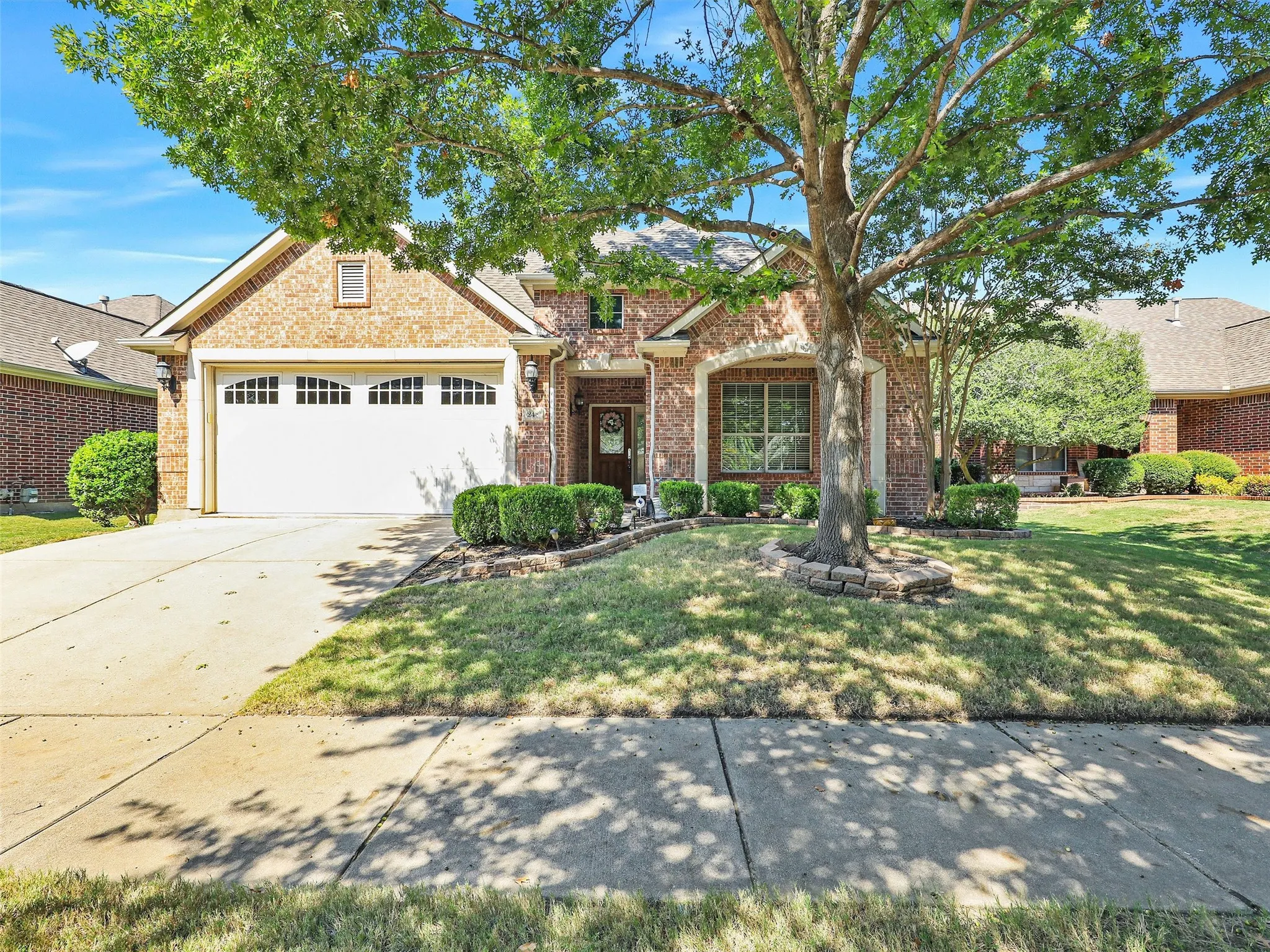 Traditional-style home with brick siding, driveway, a front lawn, and an attached garage