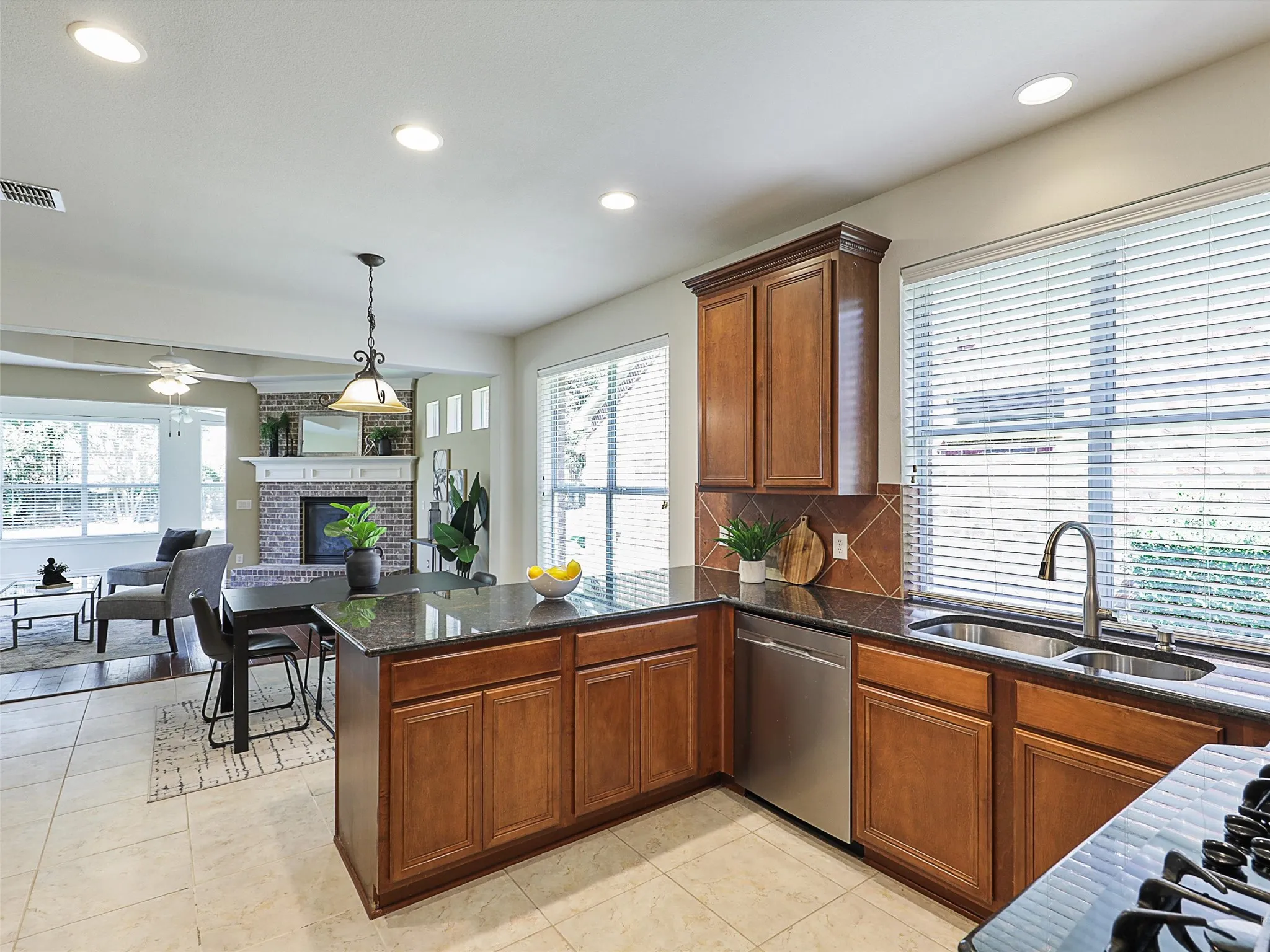 Kitchen featuring dark stone counters, a fireplace, recessed lighting, a peninsula, and gas cooktop