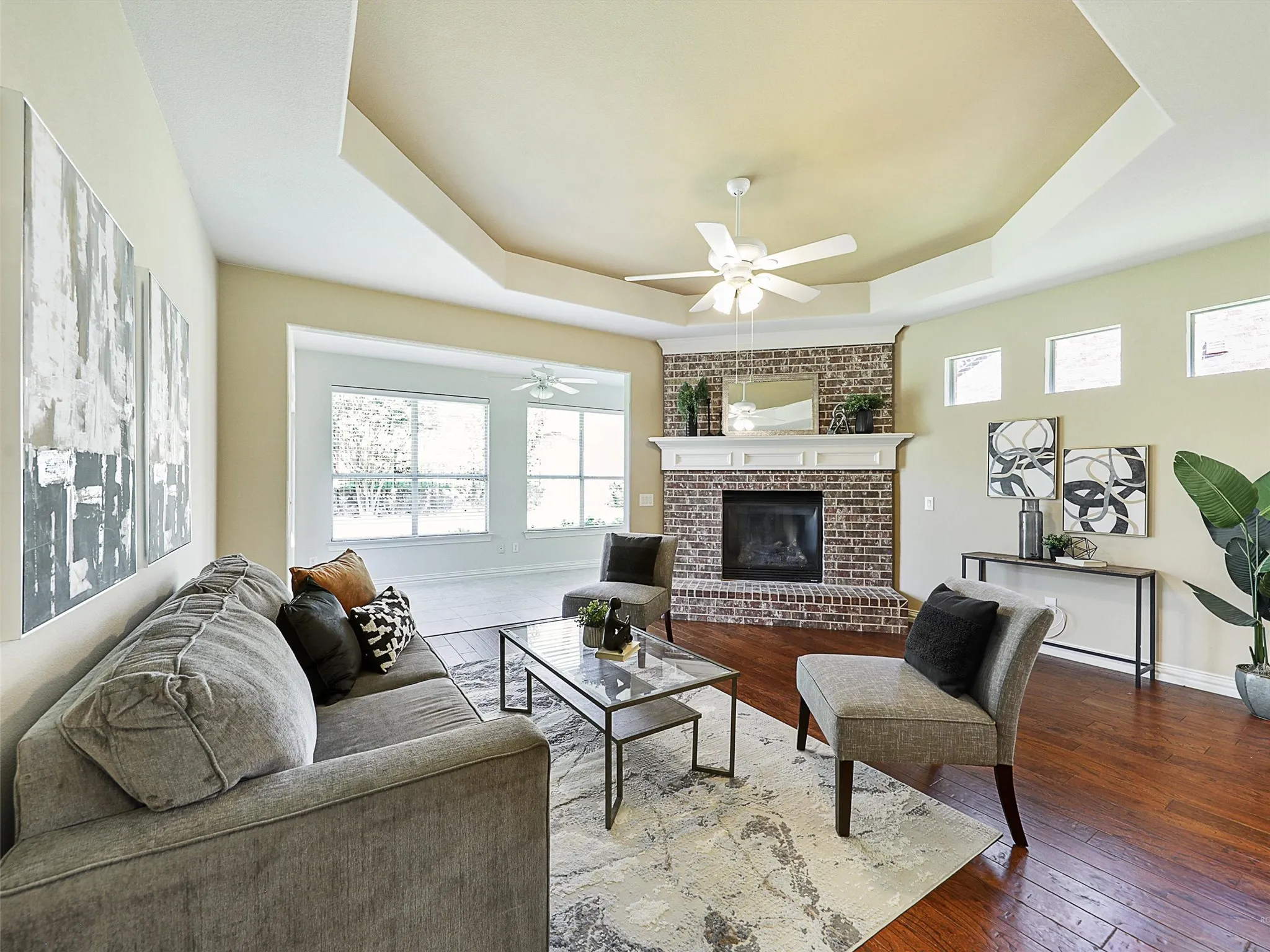 Living area featuring a raised ceiling, hardwood / wood-style floors, and a brick fireplace