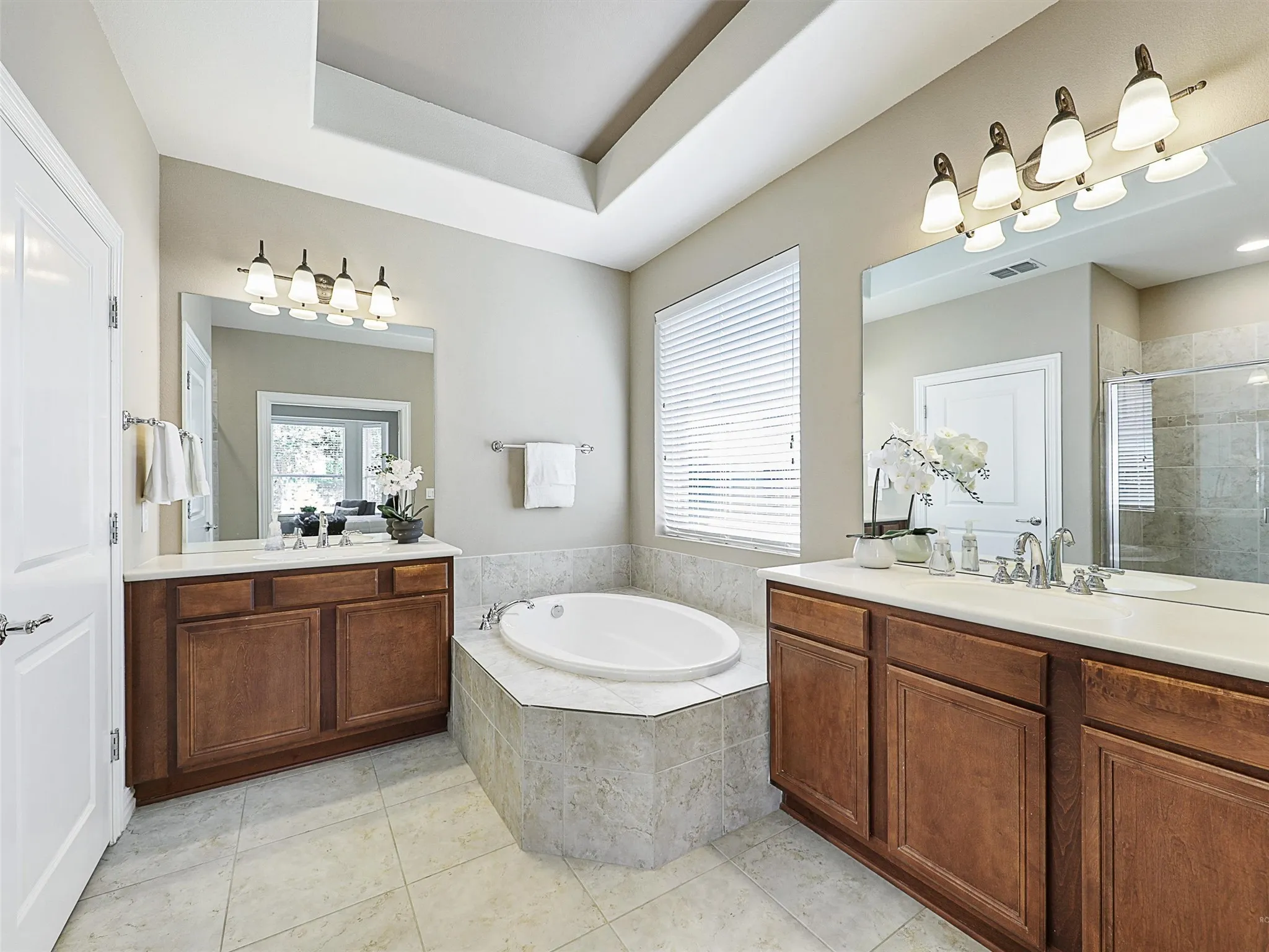 Full bathroom with a shower stall, two vanities, a bath, and light tile patterned floors