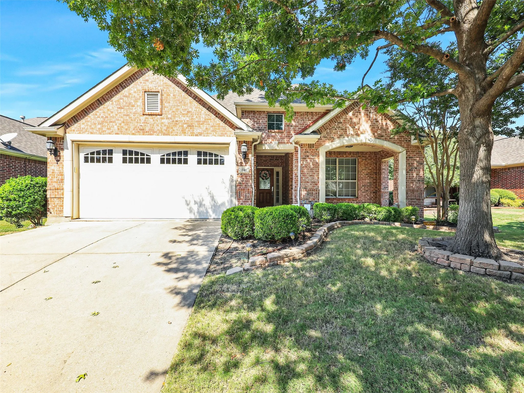 Traditional-style house featuring brick siding, driveway, a garage, and a front lawn