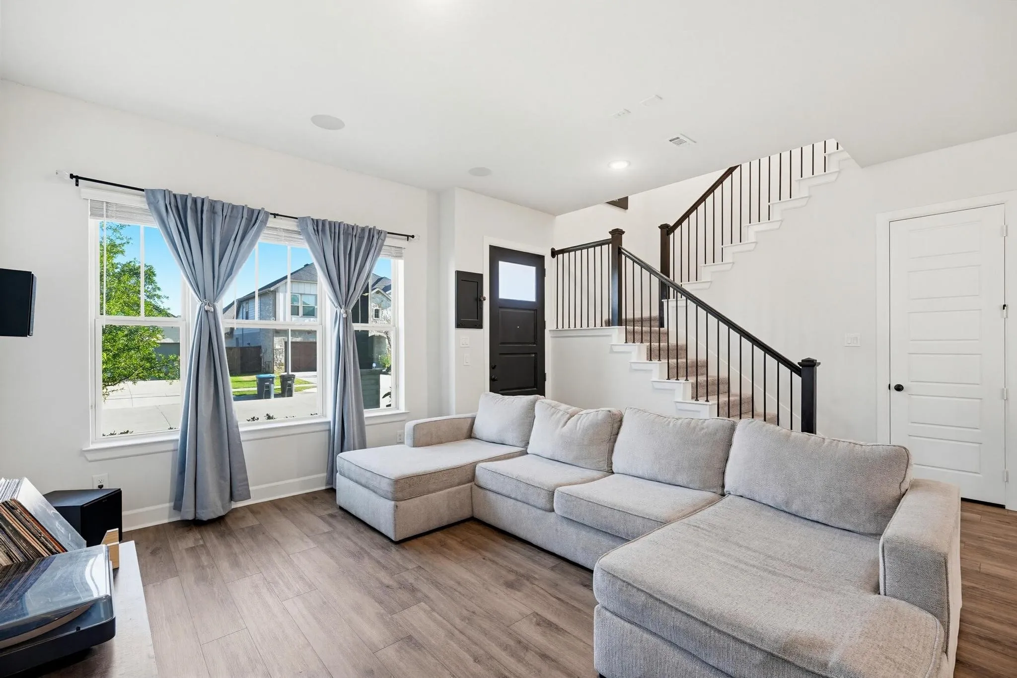 Living area featuring wood-finish flooring, white walls, and recessed lighting