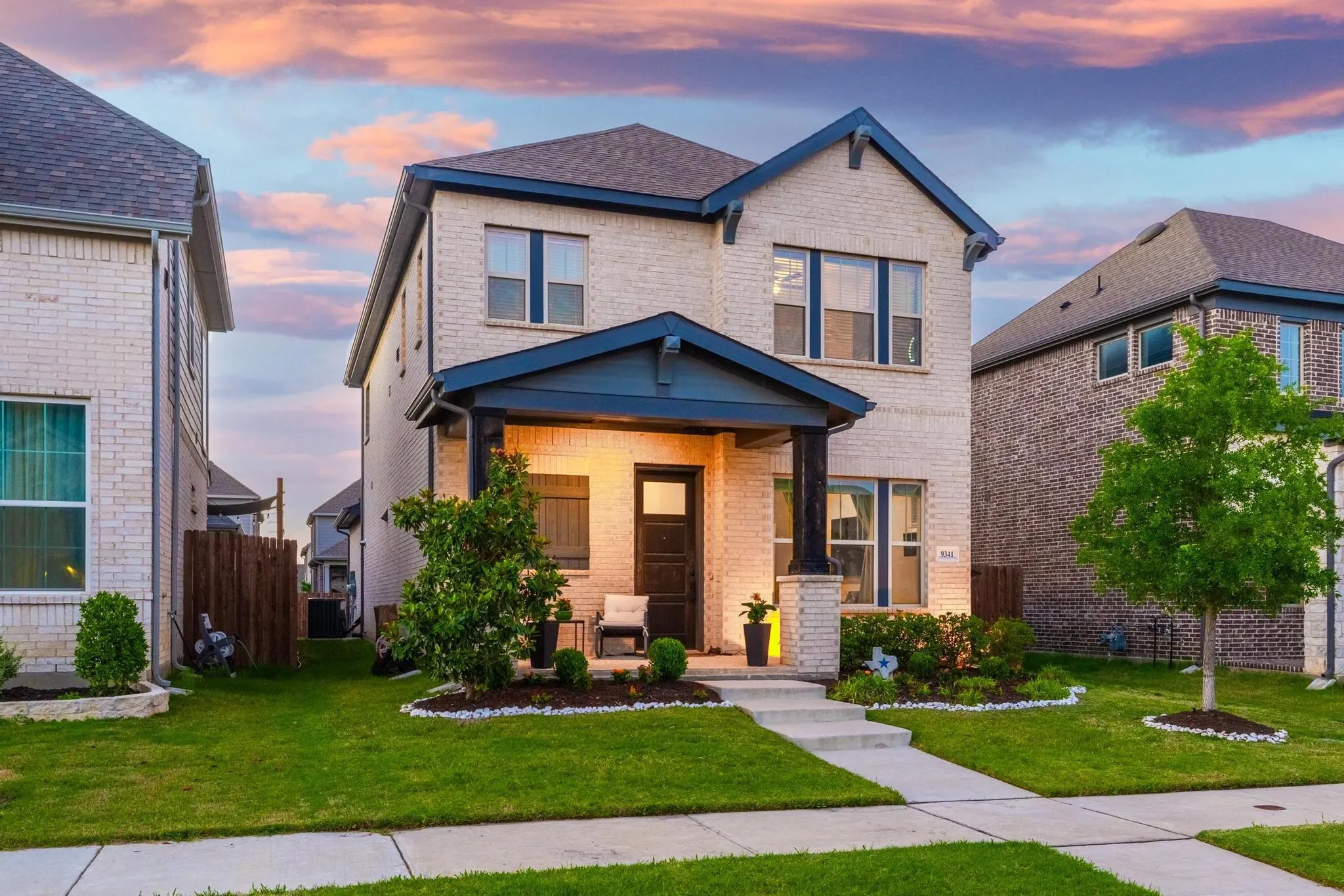 Two-story home with a light brick facade and dark blue trim