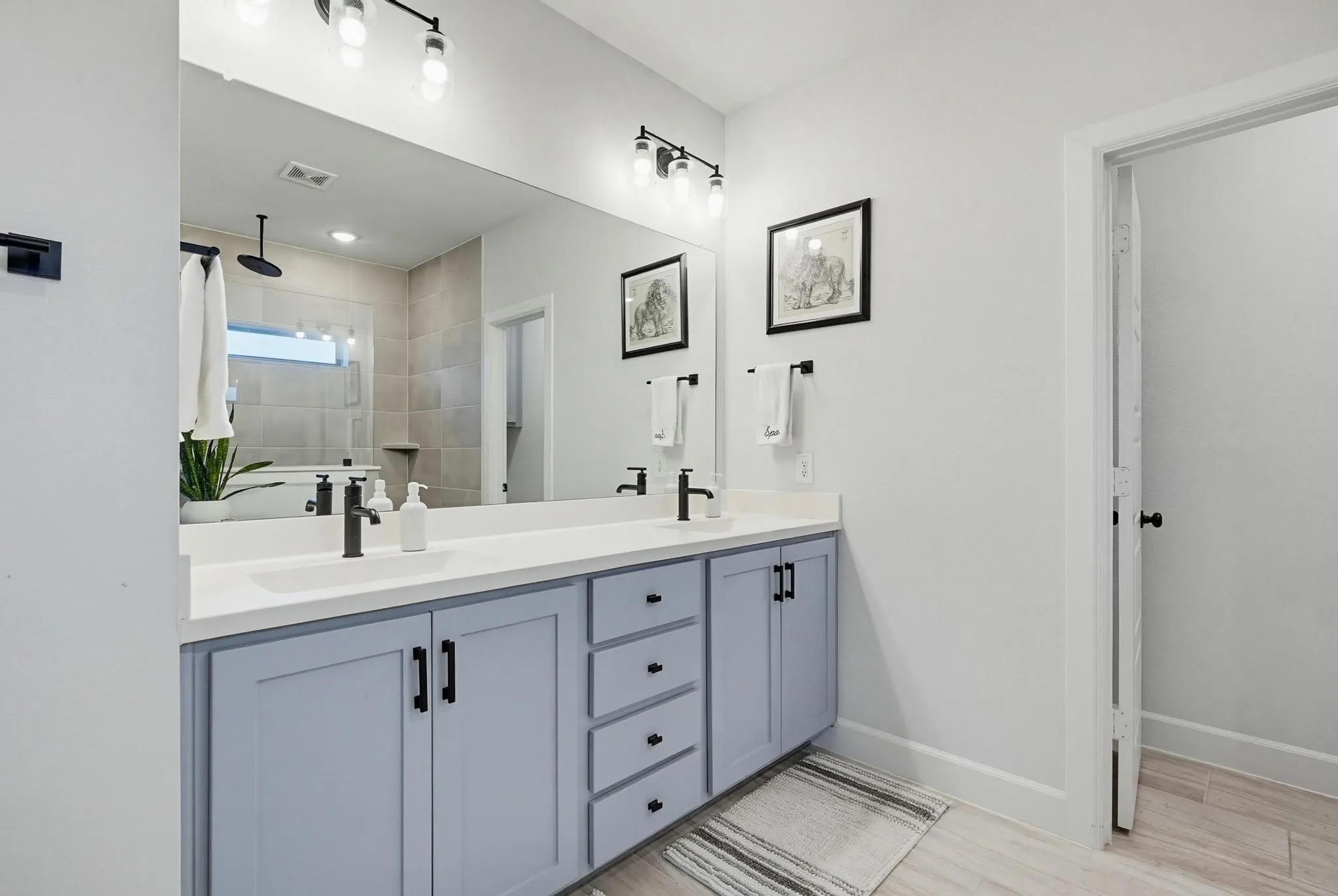 Dual vanity with light blue cabinetry, matte black hardware, and a white countertop