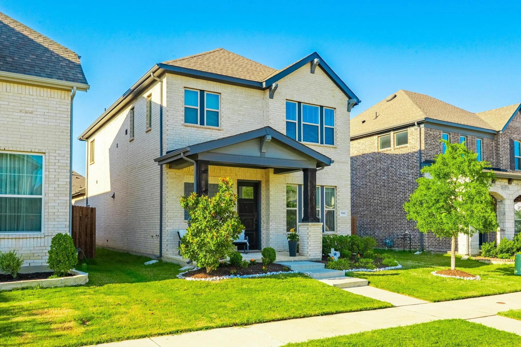 Two-story residence featuring light brick exterior and dark trim accents