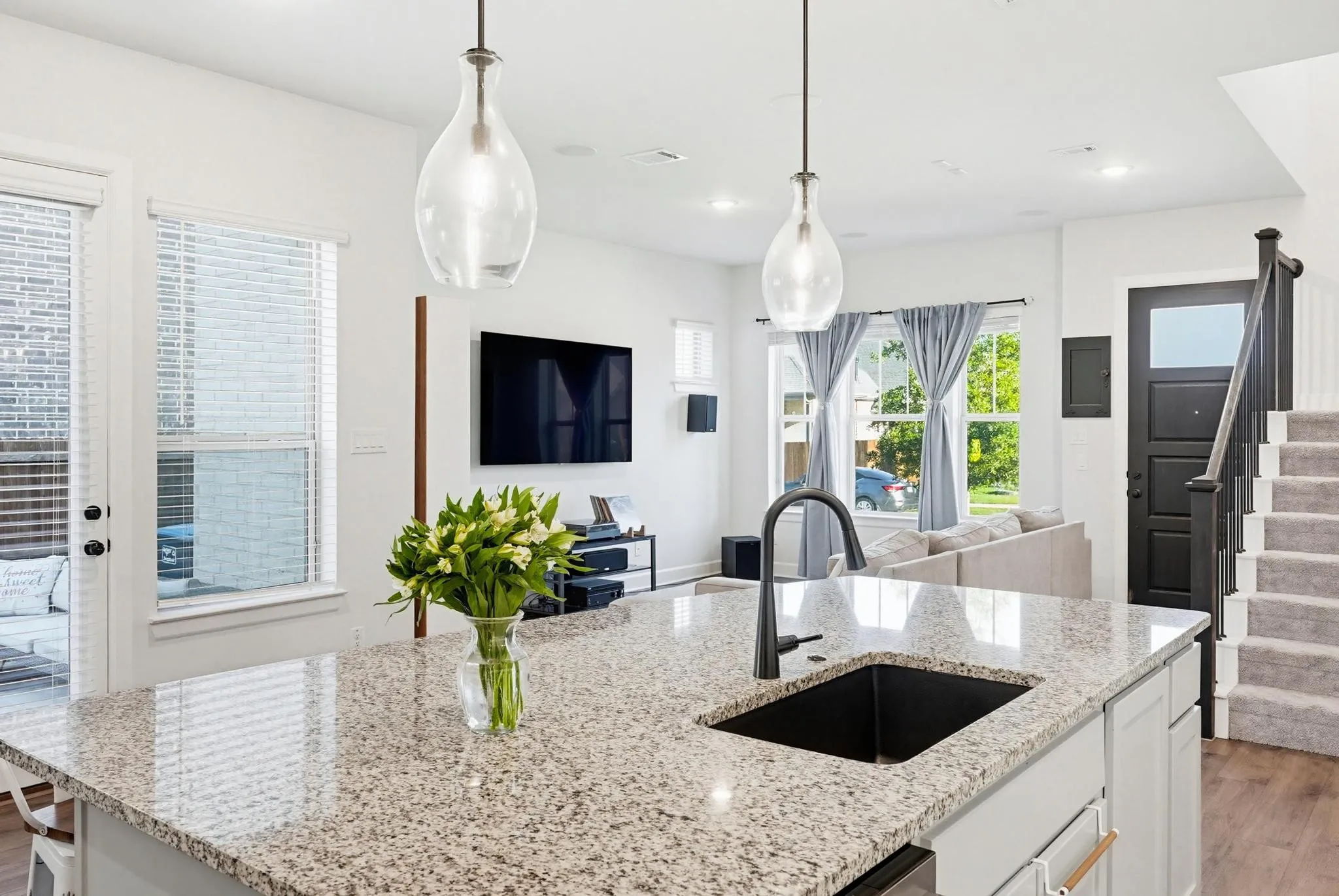 Kitchen island featuring a granite countertop with an undermount sink and matte black faucet