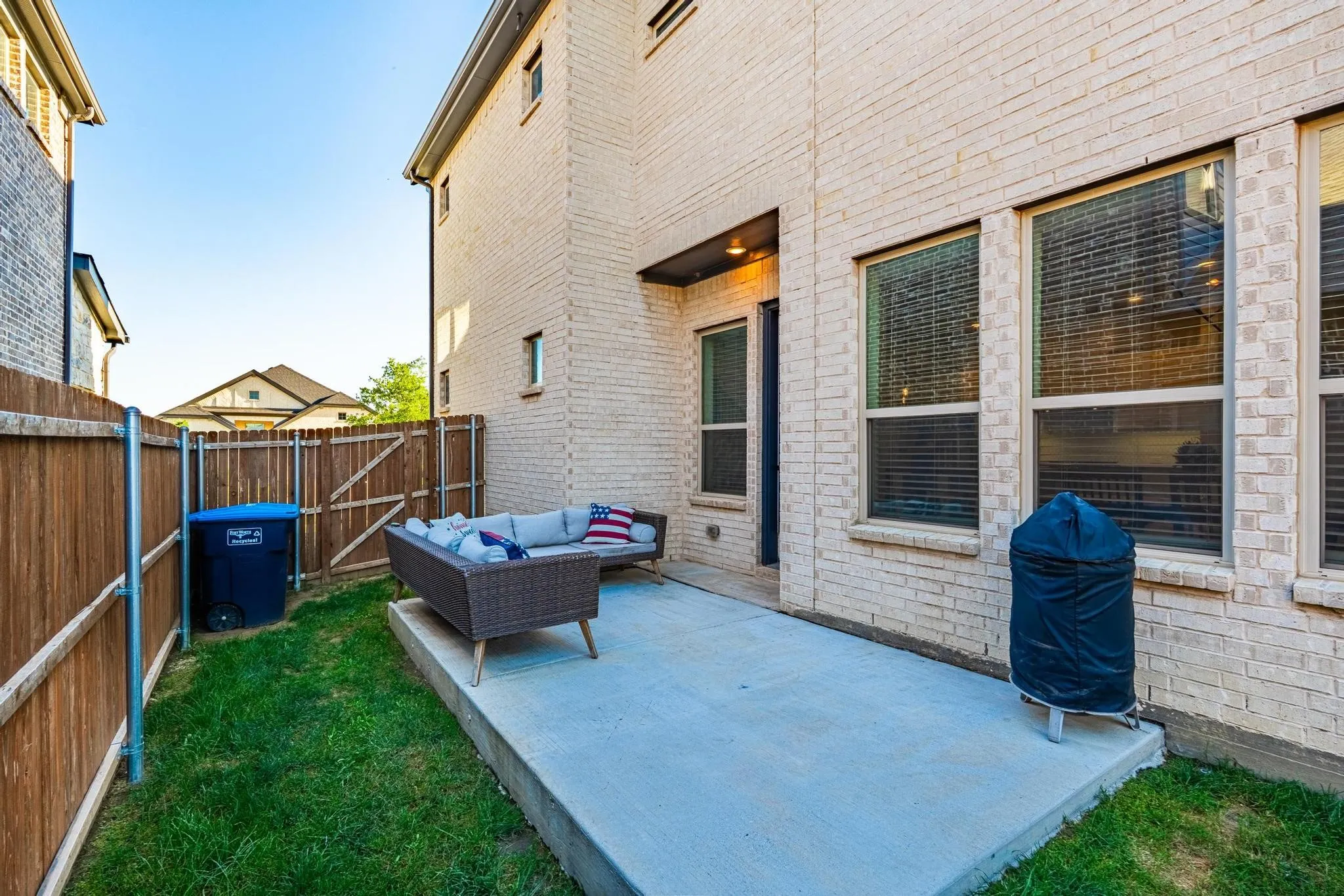 Backyard patio featuring a concrete slab, a wooden privacy fence, and a brick exterior