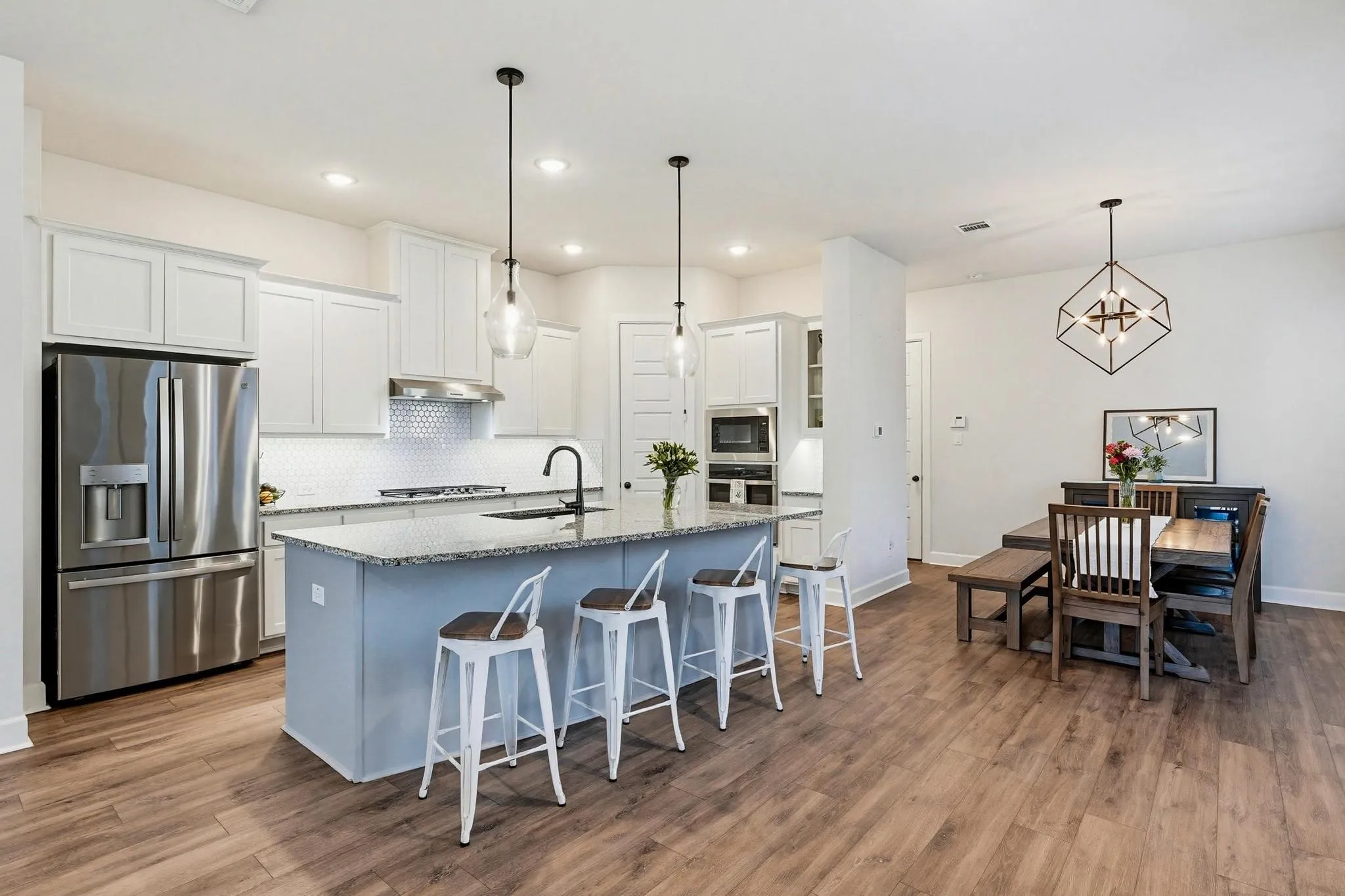 Kitchen featuring a central island with countertop seating, white shaker cabinetry, stainless steel appliances, and wood-finish flooring