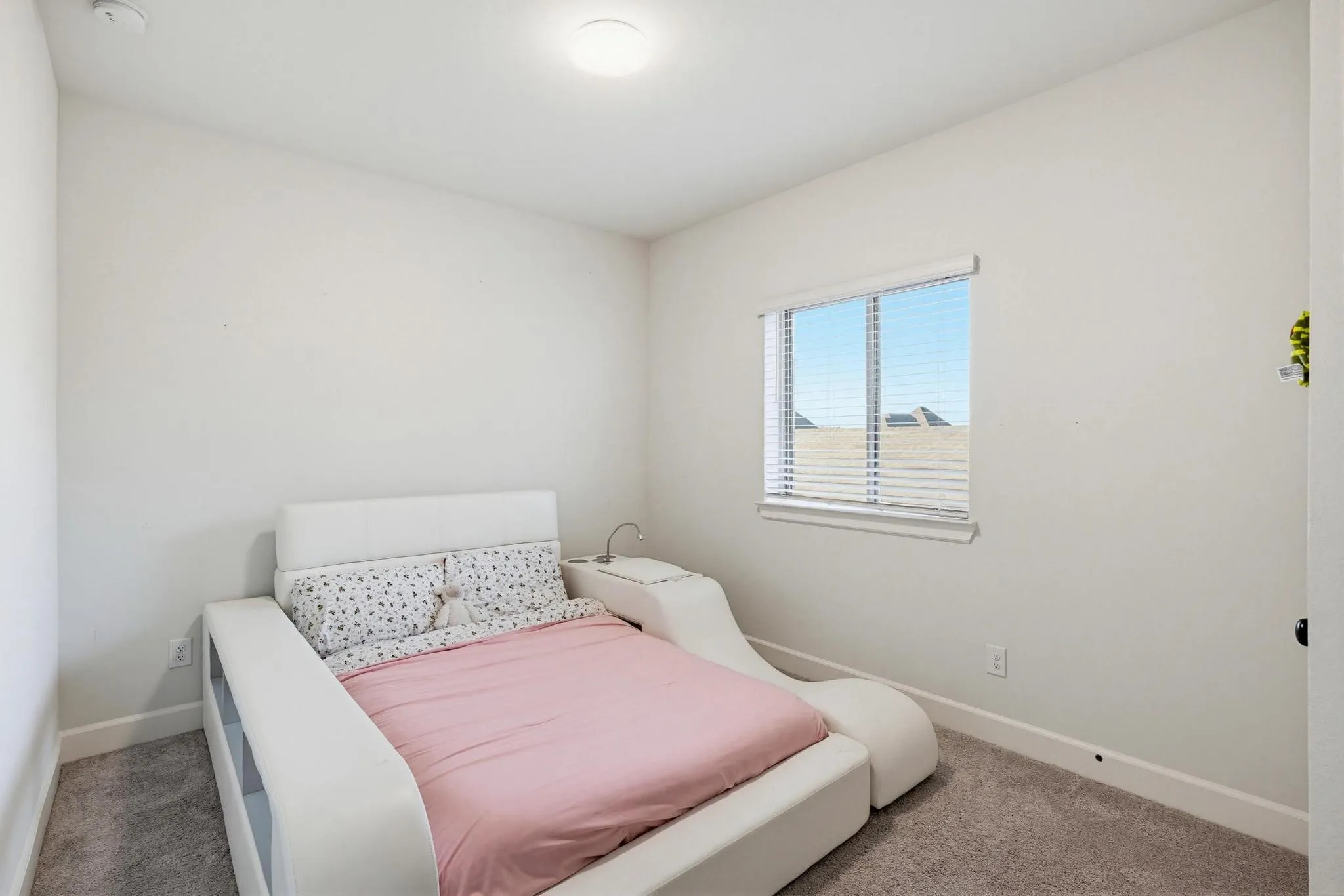 Bright room featuring a window with horizontal blinds, neutral wall paint, and gray carpet flooring