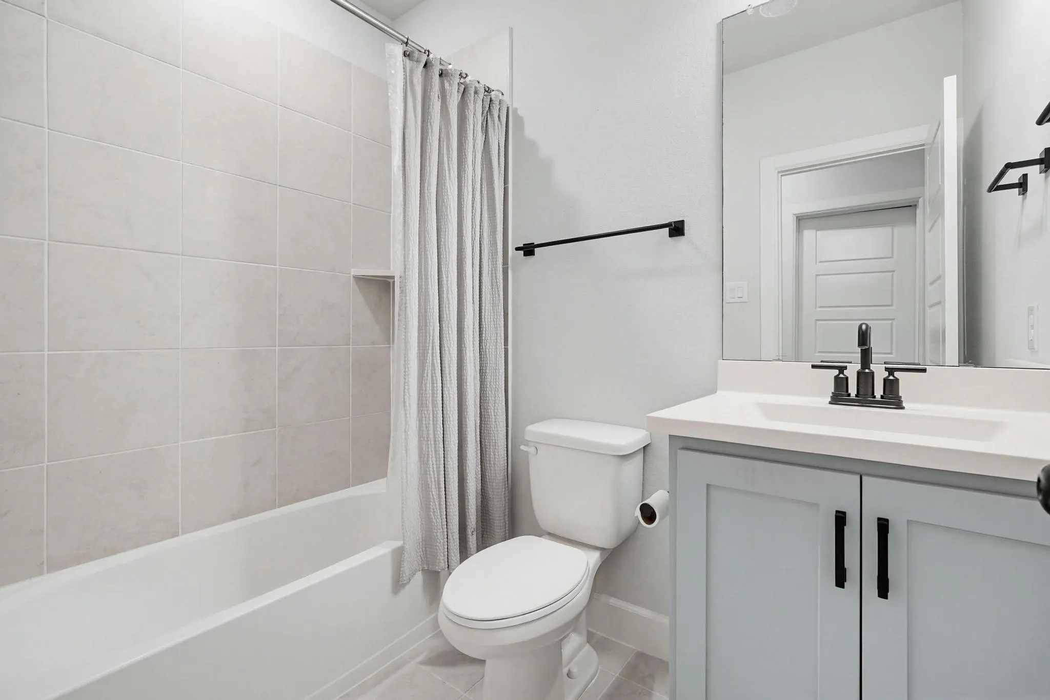 Full bathroom featuring a single vanity with a light blue shaker-style cabinet, a white countertop, and a rectangular sink