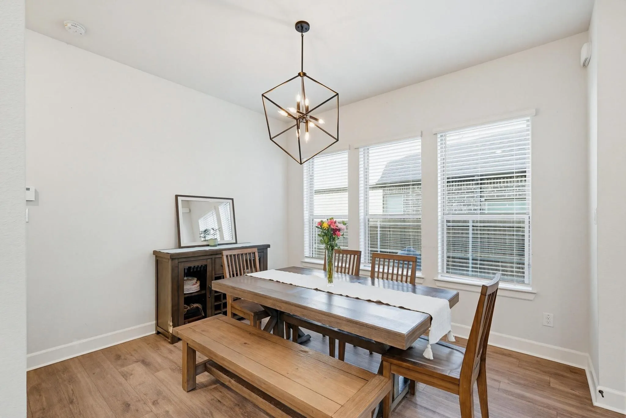 Dining area featuring wood-finish flooring, white walls, and a contemporary geometric chandelier