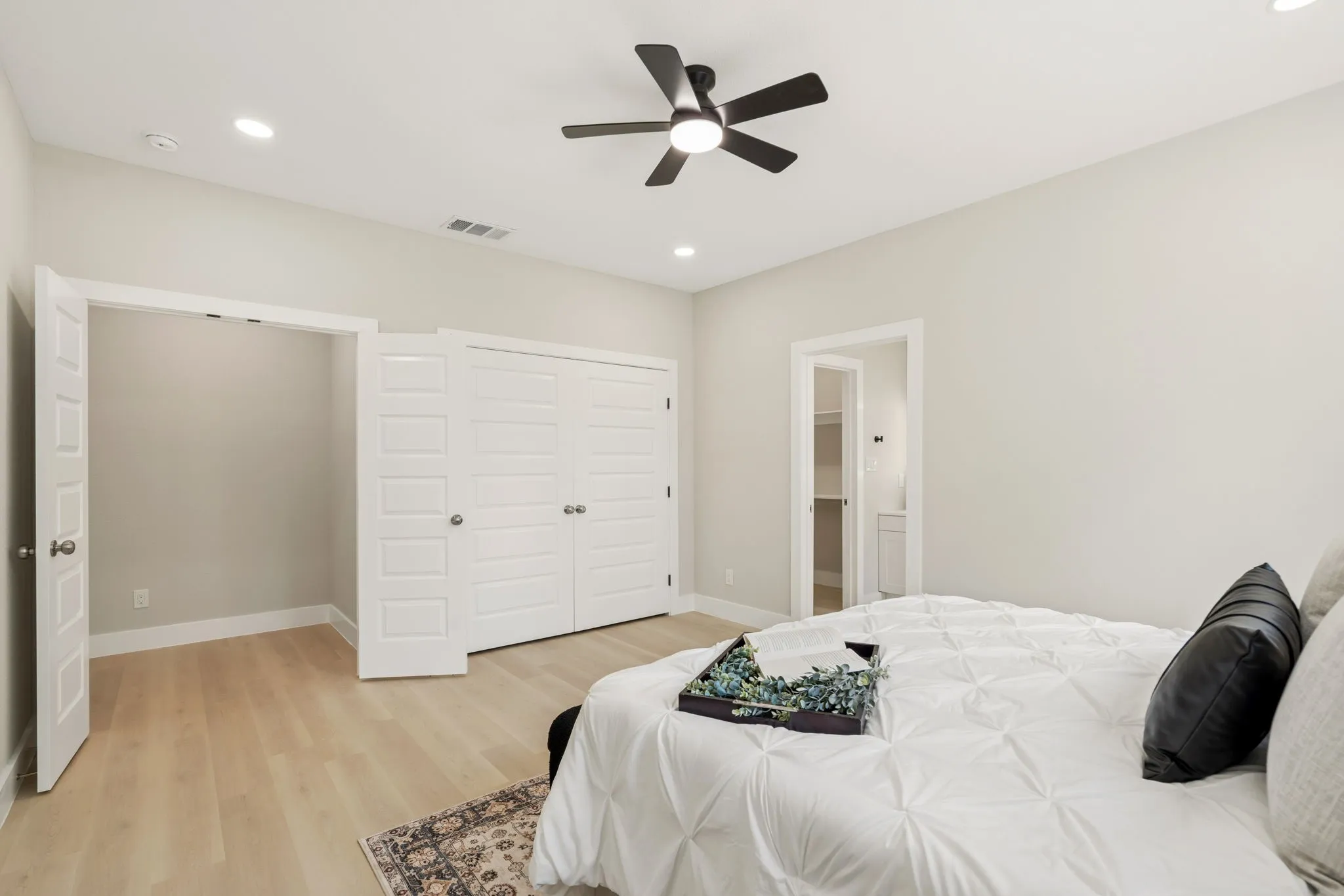 Spacious room featuring light wood-finish flooring, recessed lighting, and a ceiling fan with matte black accents