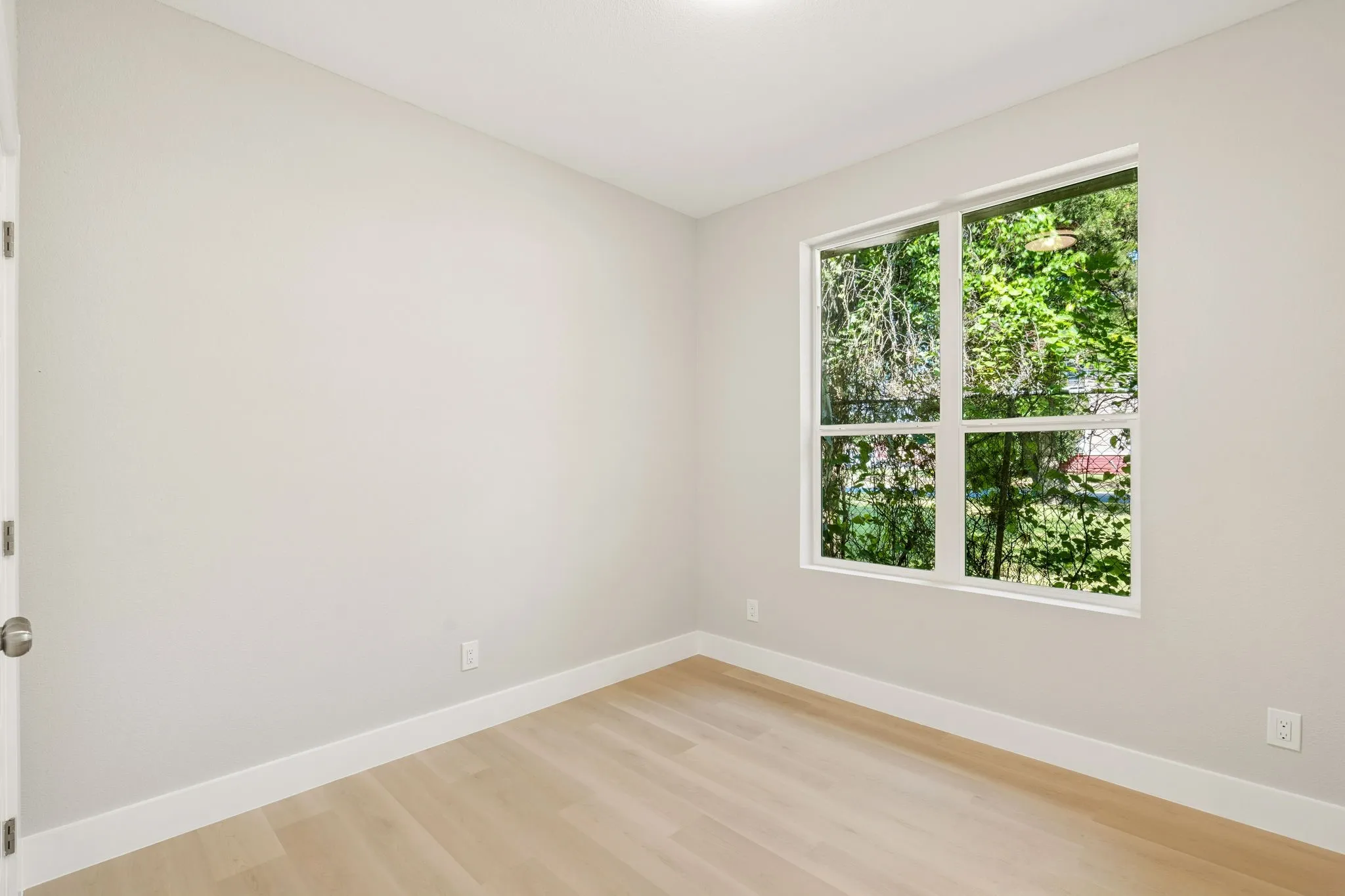 Light-toned wood-finish flooring complements the neutral wall color