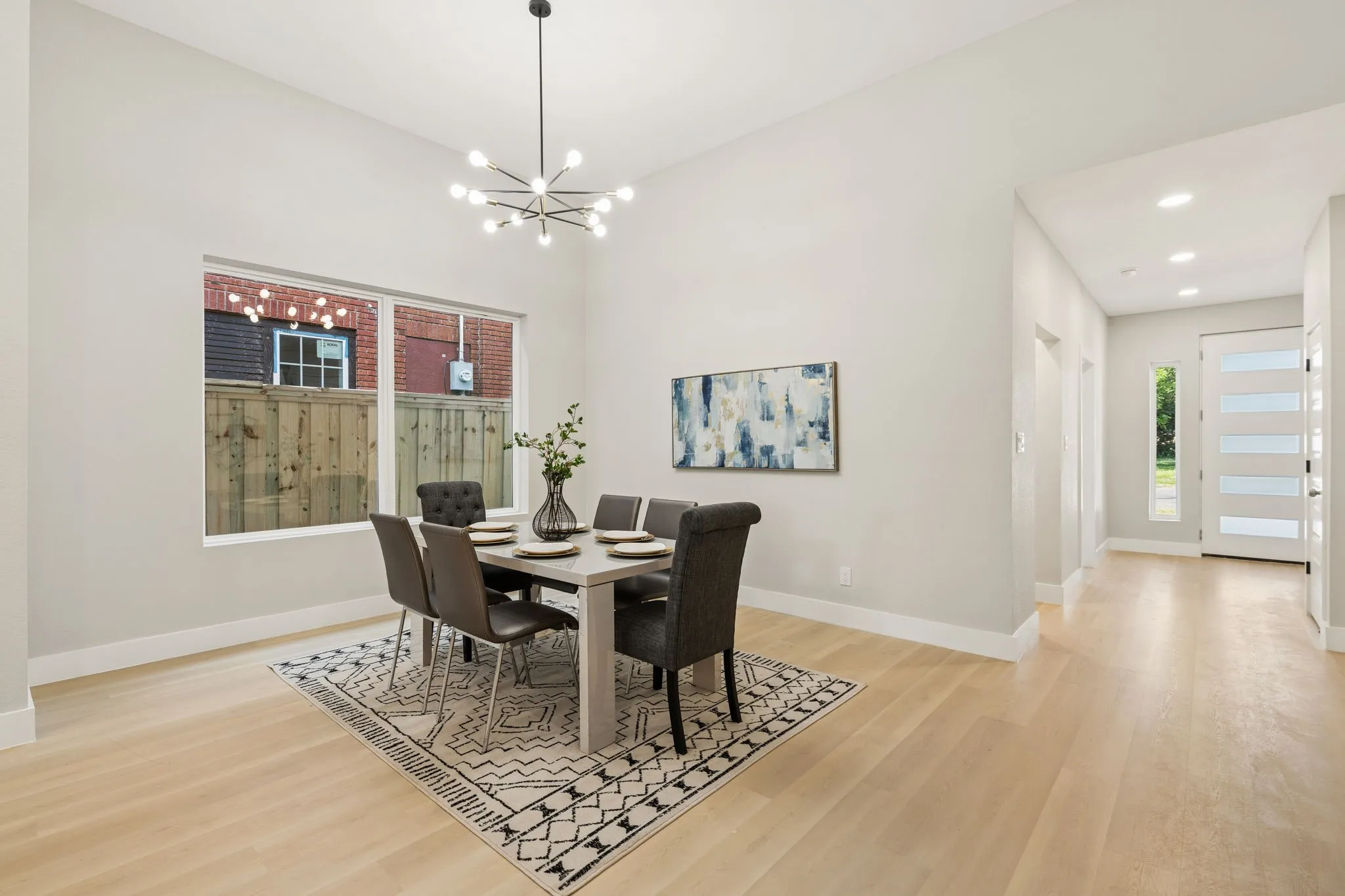 Spacious dining area featuring wood-finish flooring, a contemporary chandelier, and a large window