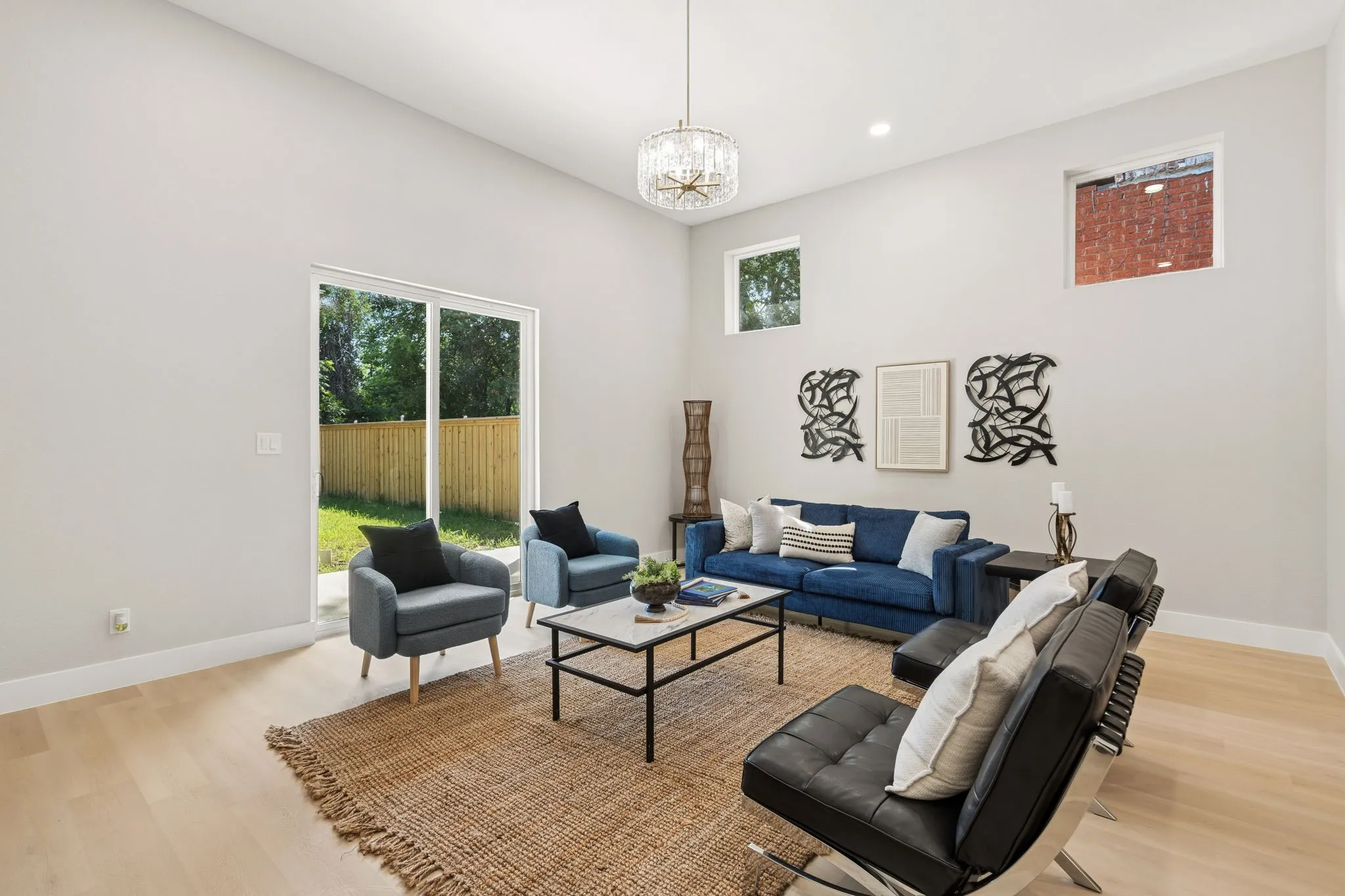 High ceilings define this living space, featuring a modern chandelier and recessed lighting