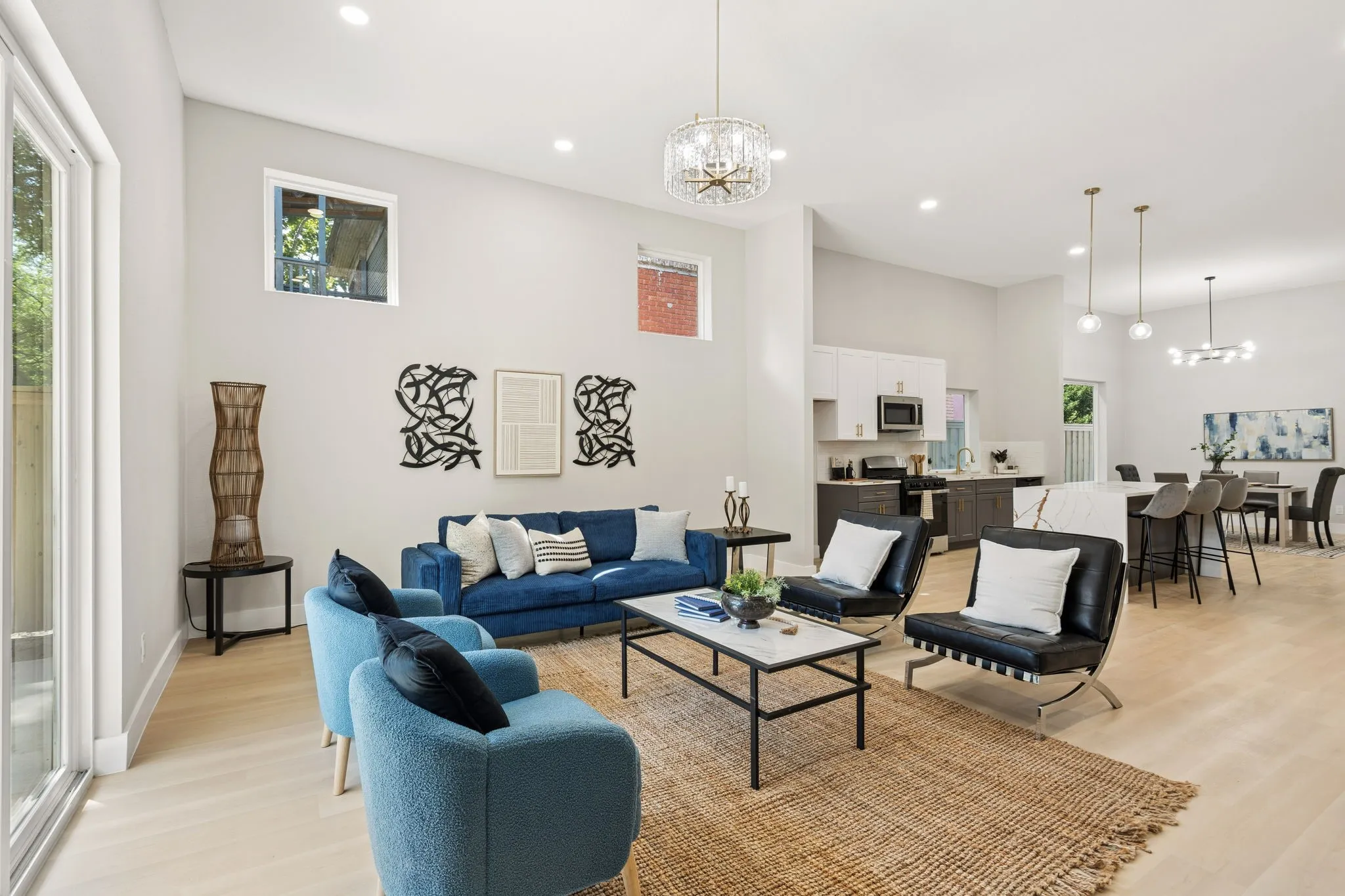 Open-concept living area featuring light wood-finish flooring, recessed lighting, a modern chandelier, and a kitchen with an island