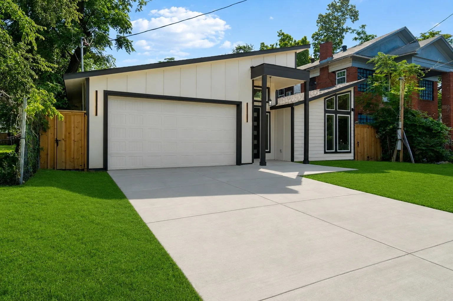Modern white and black exterior with a prominent garage, a covered entry, and a pitched roofline