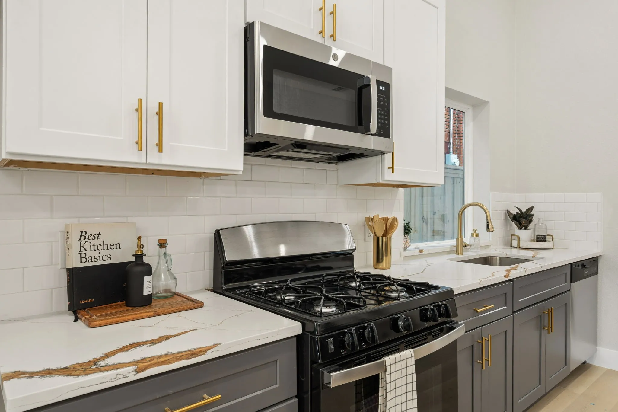 Modern kitchen featuring white upper cabinetry and gray lower cabinetry with gold-toned hardware