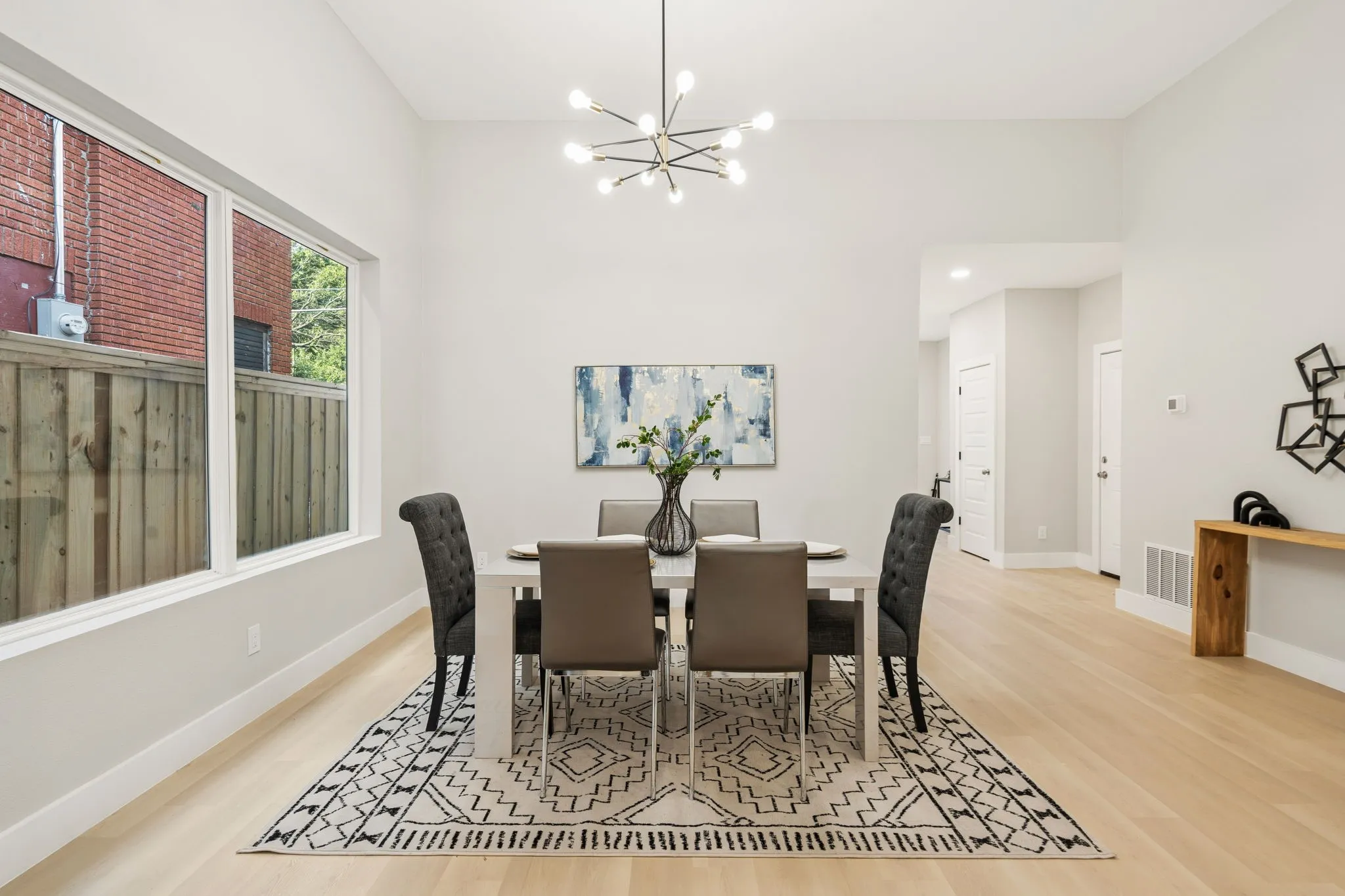 Spacious dining area featuring high vaulted ceilings, light wood-finish flooring, and a contemporary linear chandelier