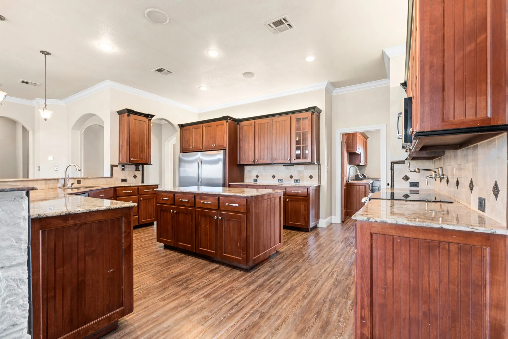 Kitchen featuring custom built in fridge area, an island, granite countertops, and built ins.